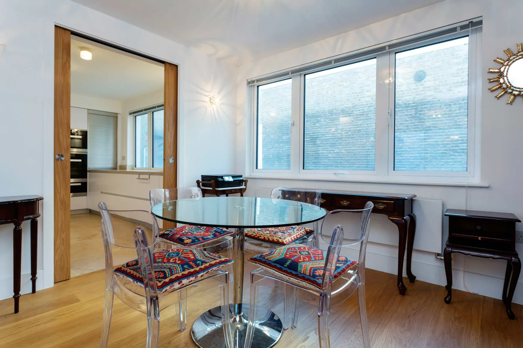 Comedor con una mesa de vidrio y asientos con estampados coloridos.