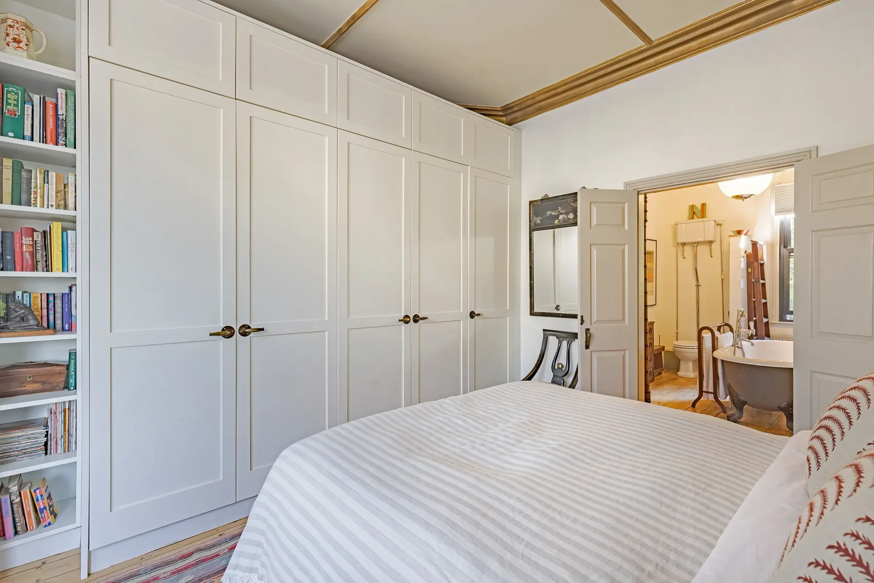 A bedroom with built-in wardrobes and a doorway to an adjoining bathroom.