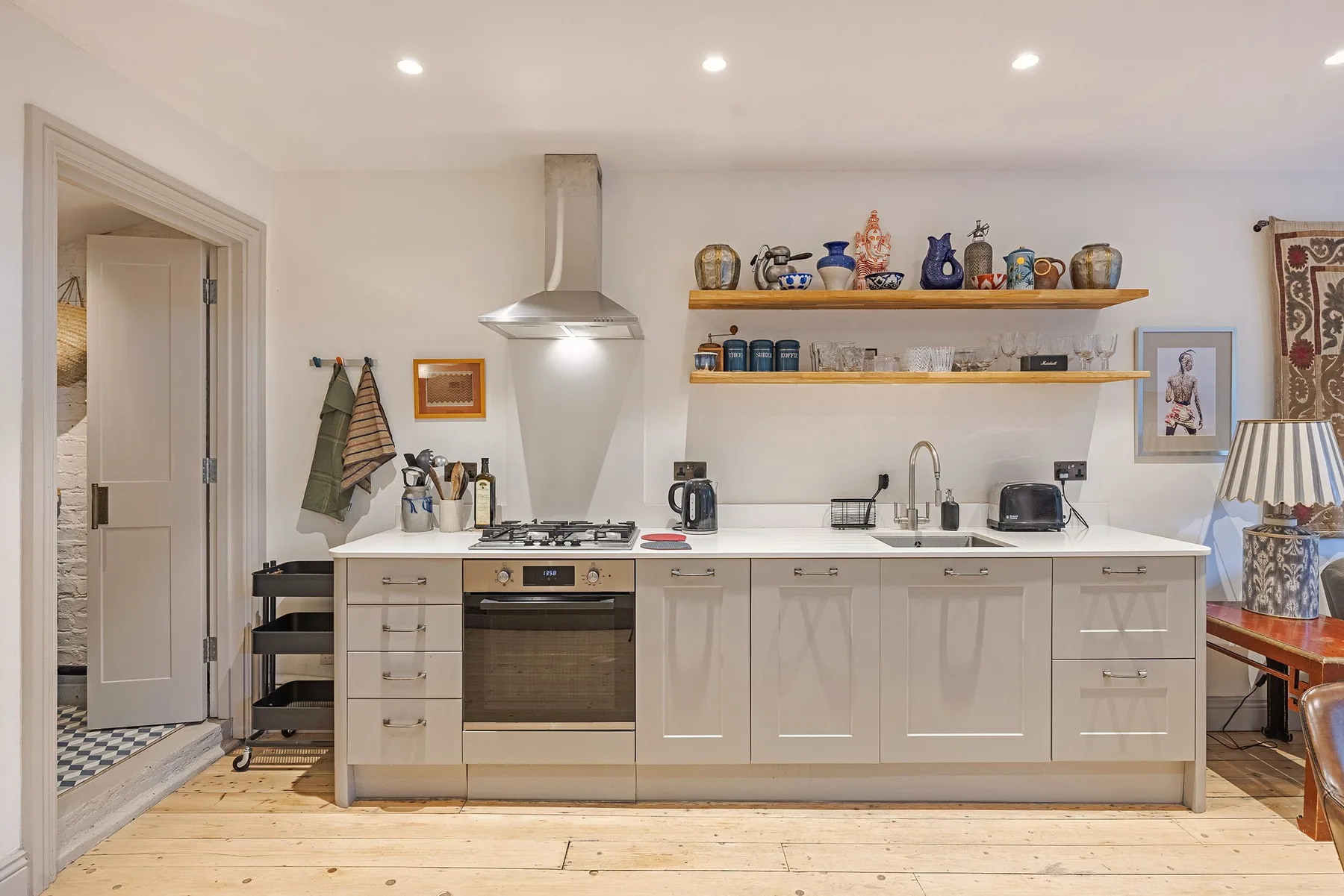 Una cocina luminosa con gabinetes blancos, una estufa y estantes abiertos.
