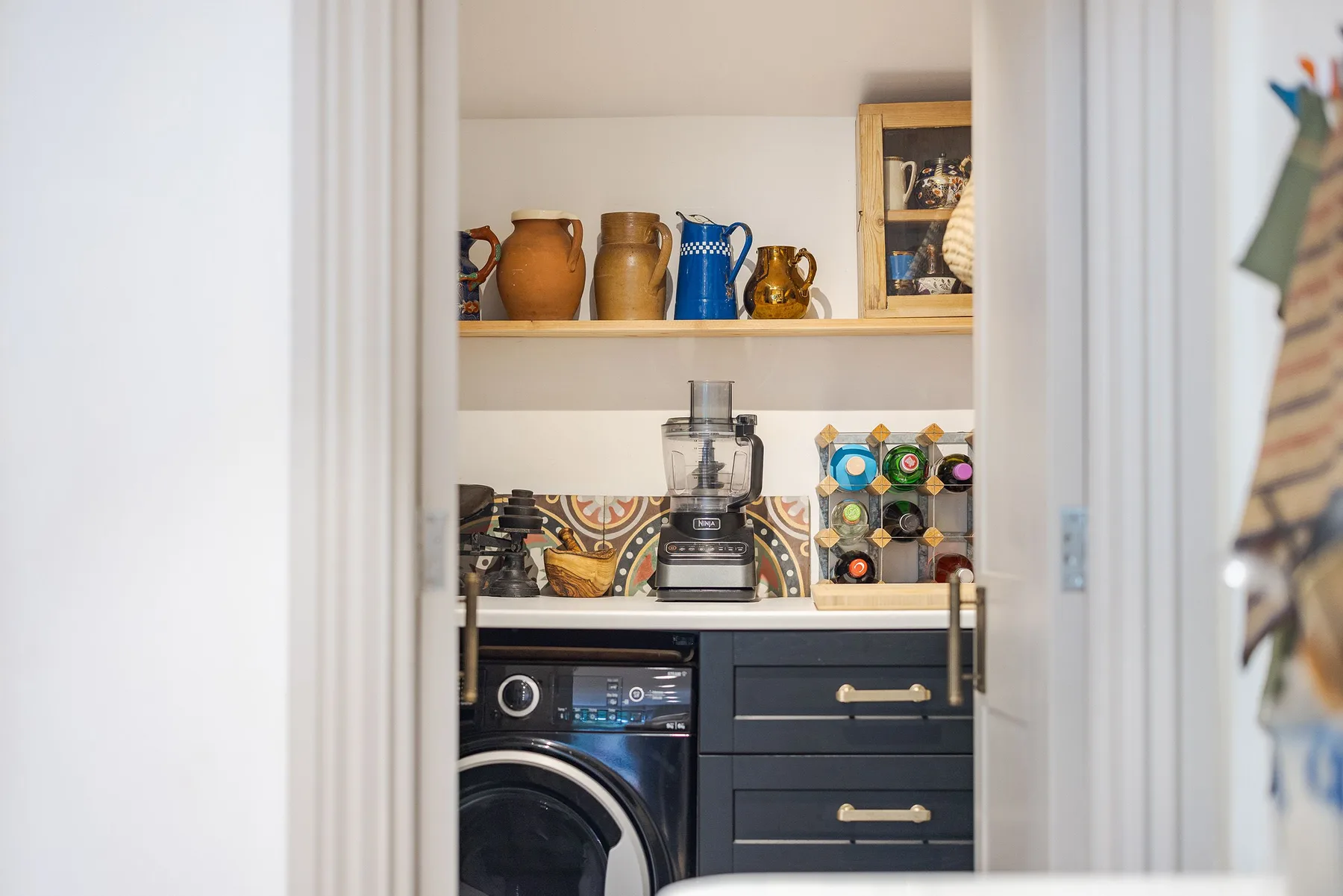 A laundry area with a washing machine, countertop, and open shelves.