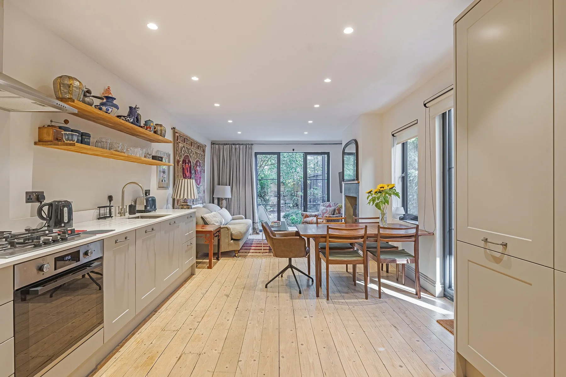 A bright open-plan kitchen and dining area with windows overlooking greenery.