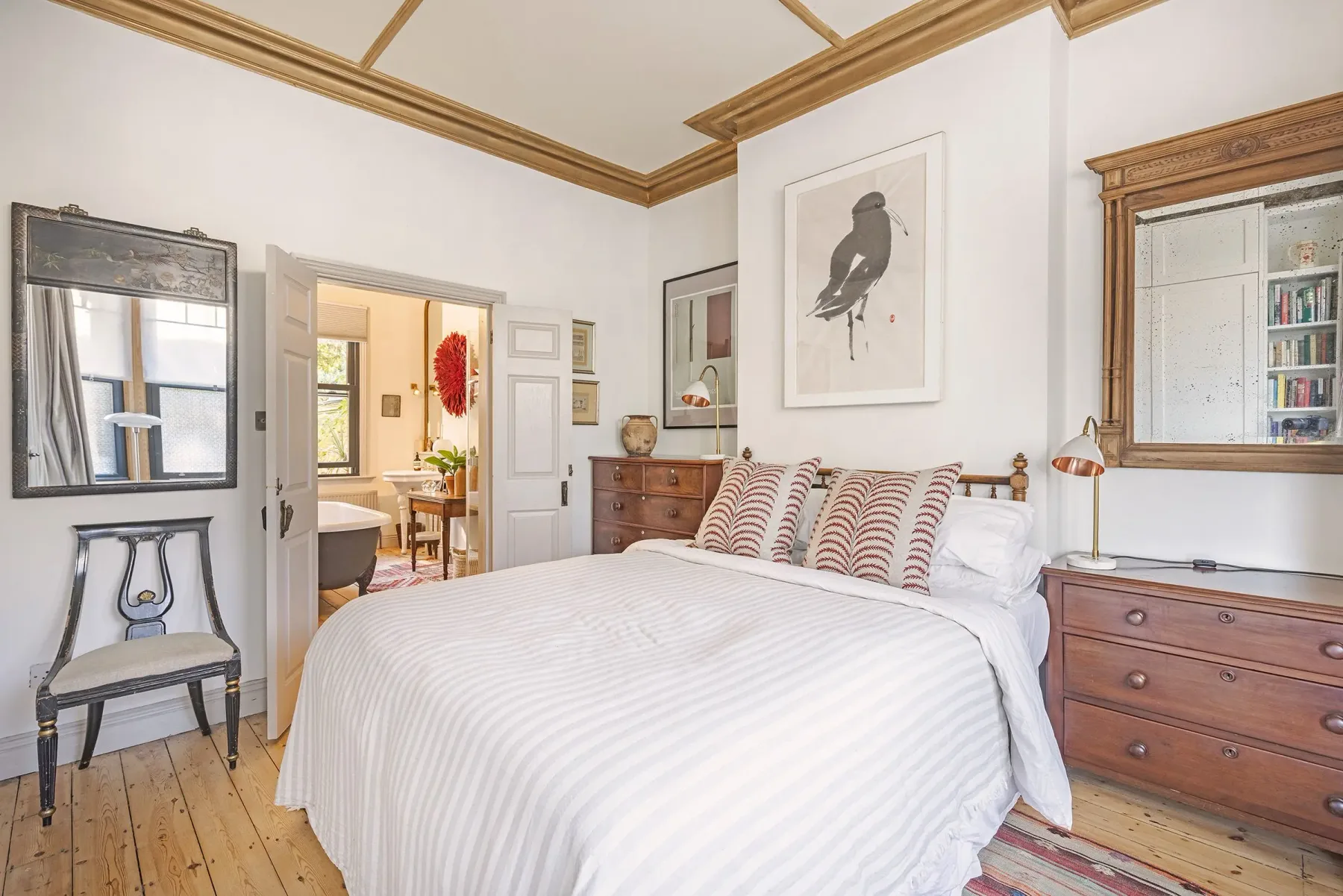 A bright bedroom with a large bed and framed bird artwork.