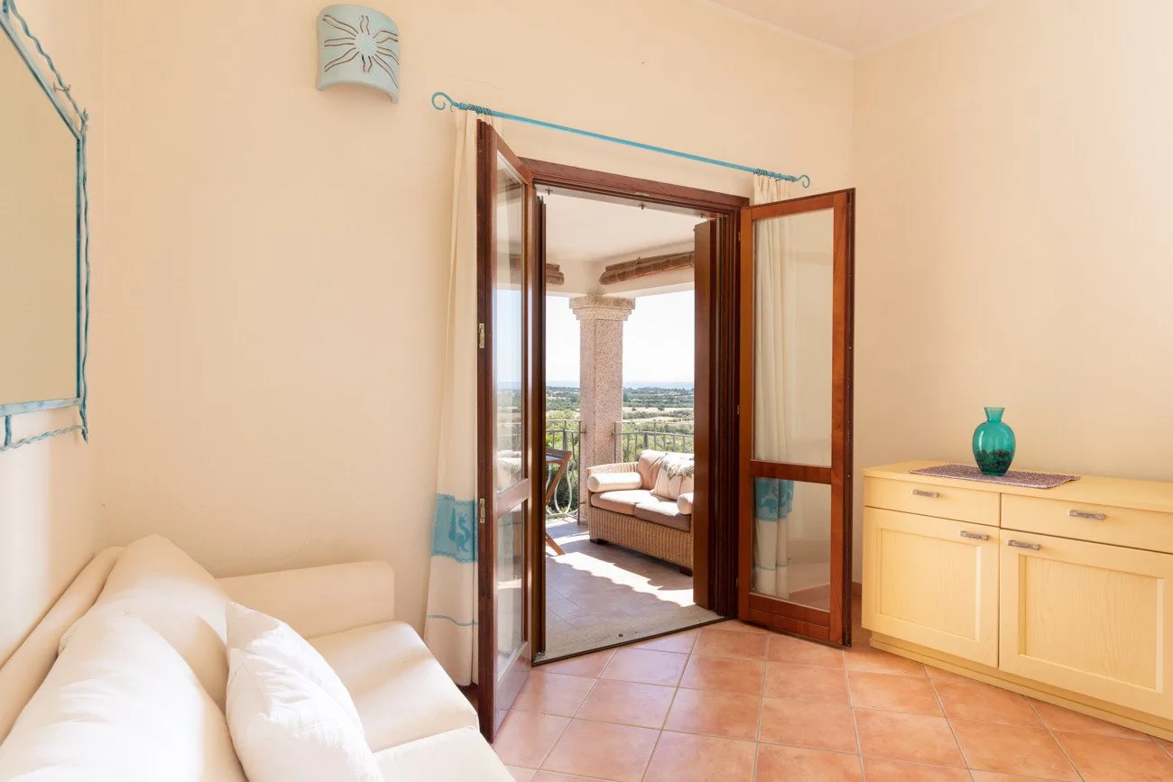 A bright sitting room opens through wooden doors onto a covered terrace.