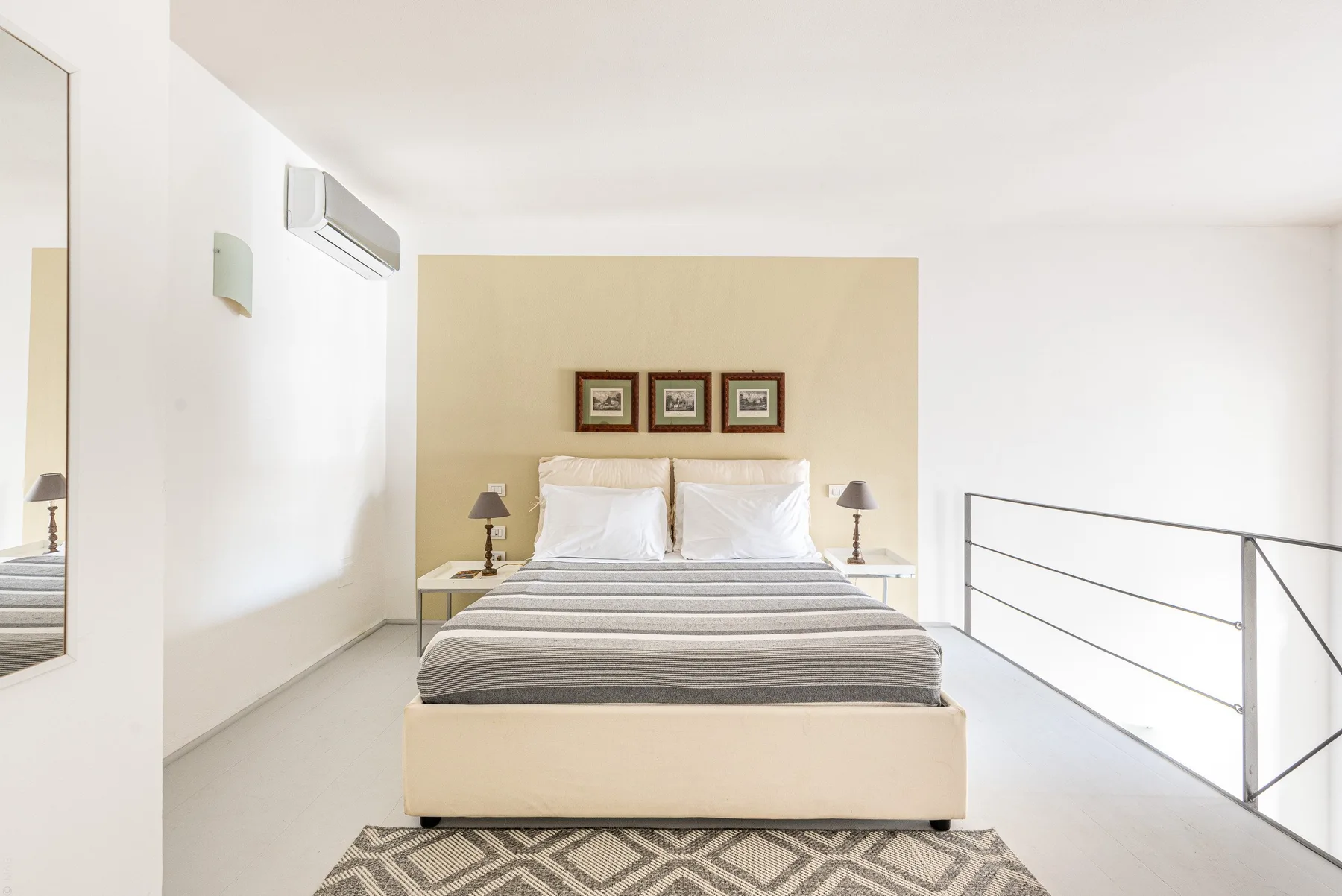 Un dormitorio luminoso con una cama bajo tres cuadros enmarcados.