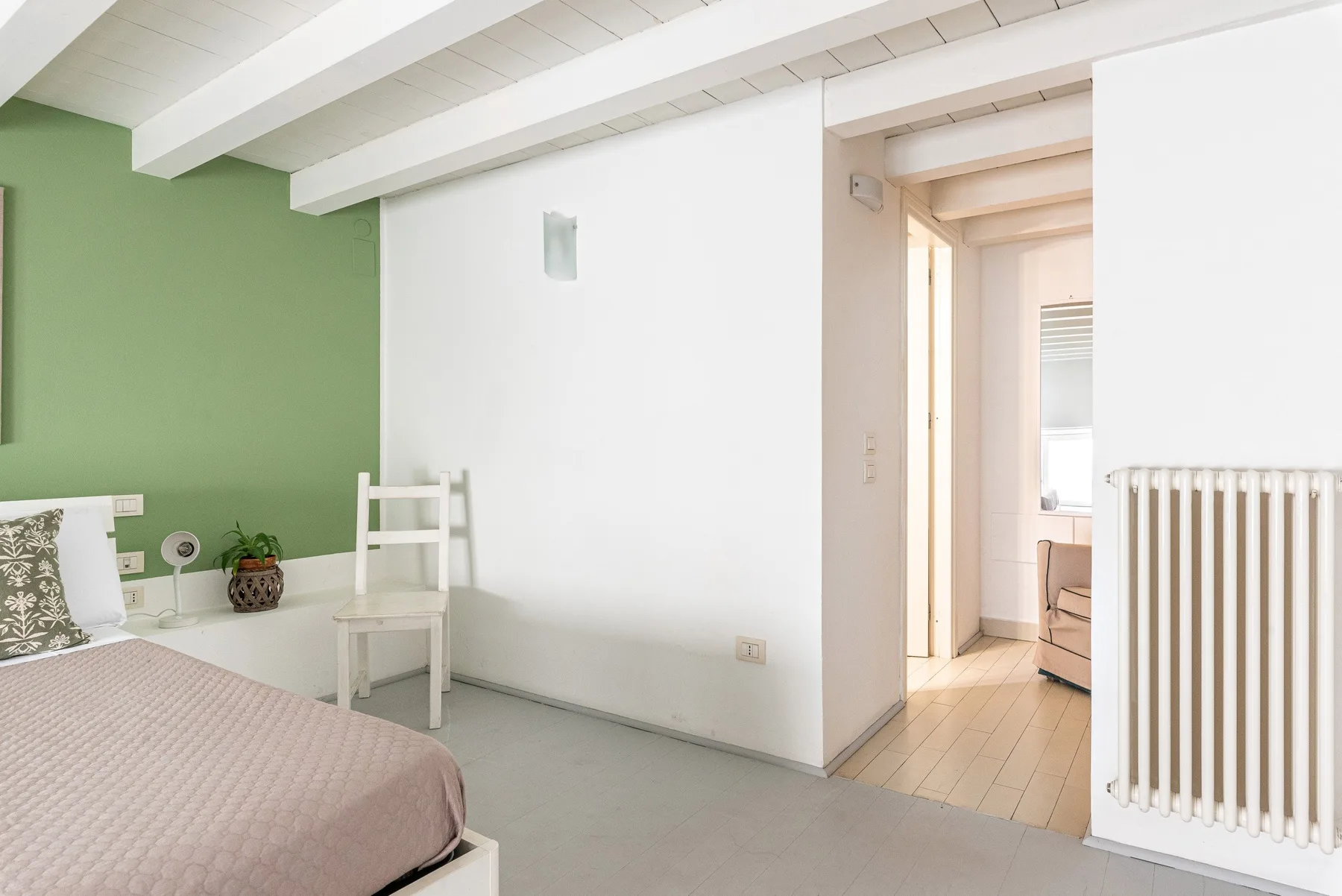 Un dormitorio con una cama junto a una pared verde y una puerta abierta.