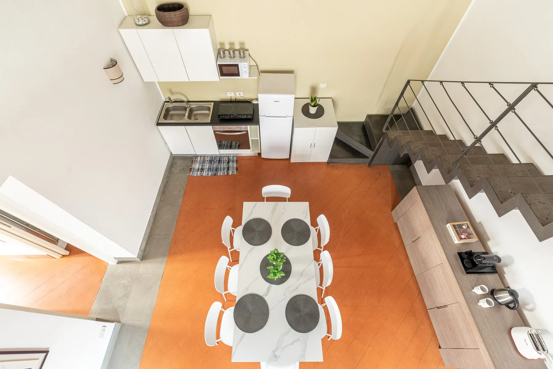 Una cocina compacta y zona de comedor con una mesa junto a una escalera.
