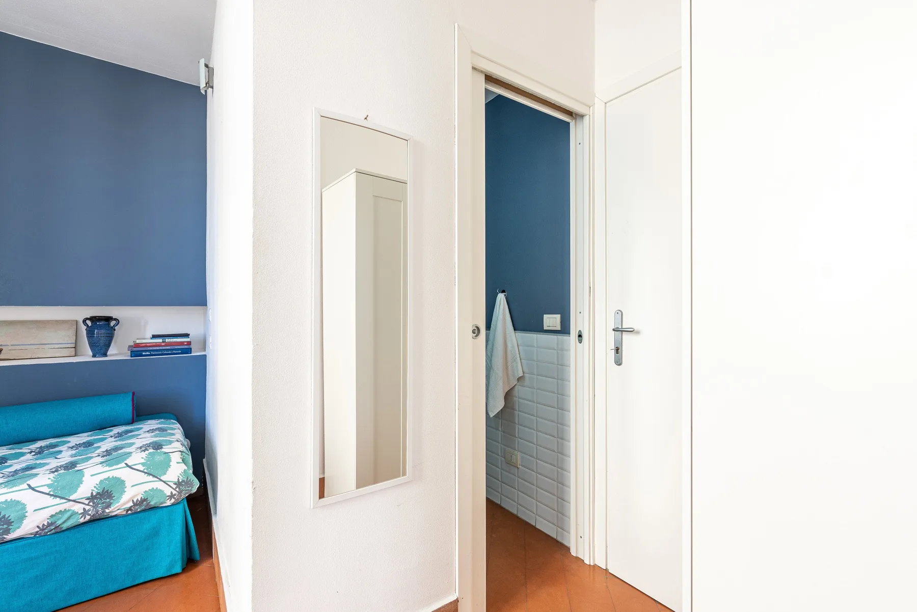 Un dormitorio con una cama junto a una puerta abierta hacia un baño.