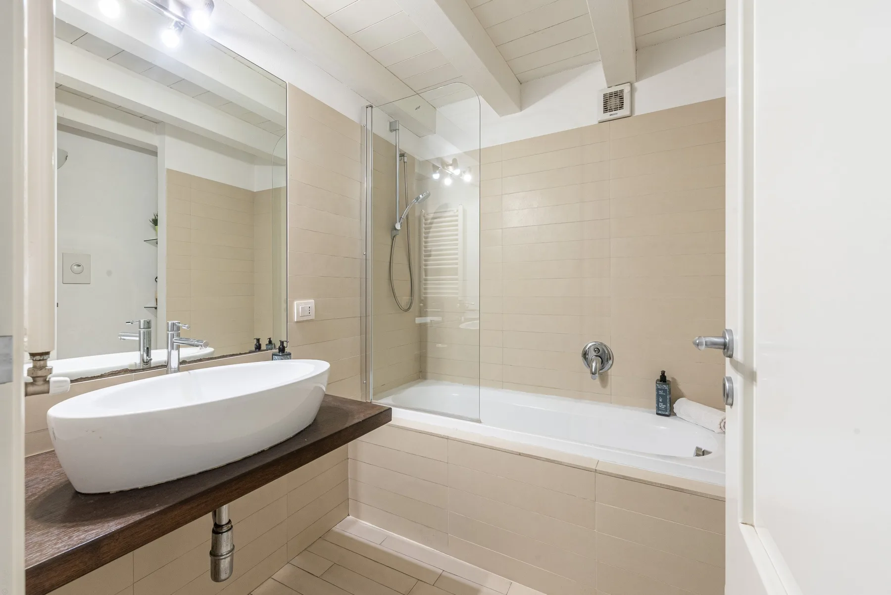 Un baño luminoso con lavabo sobre encimera junto a una bañera con ducha.