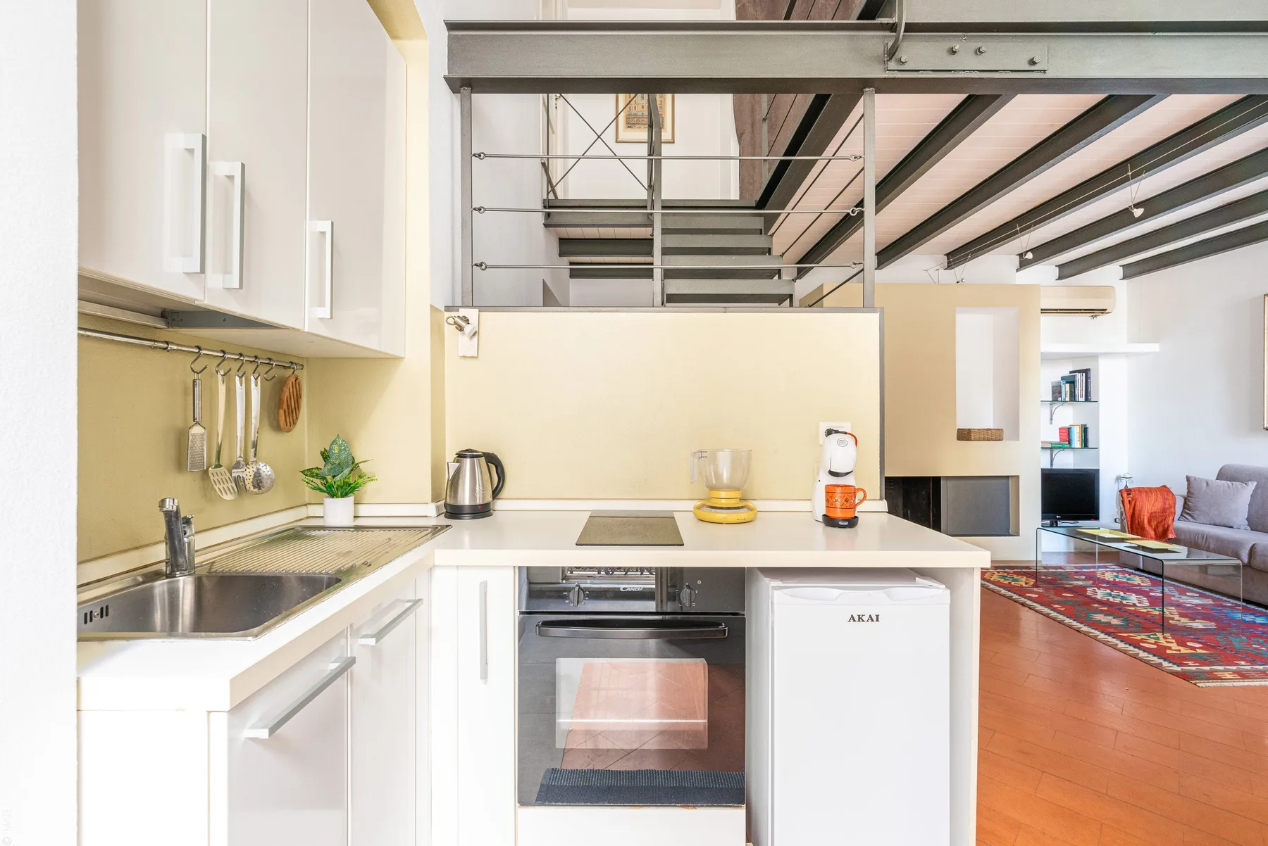 Una cocina luminosa con encimera, fregadero y electrodomésticos se abre a una sala de estar.