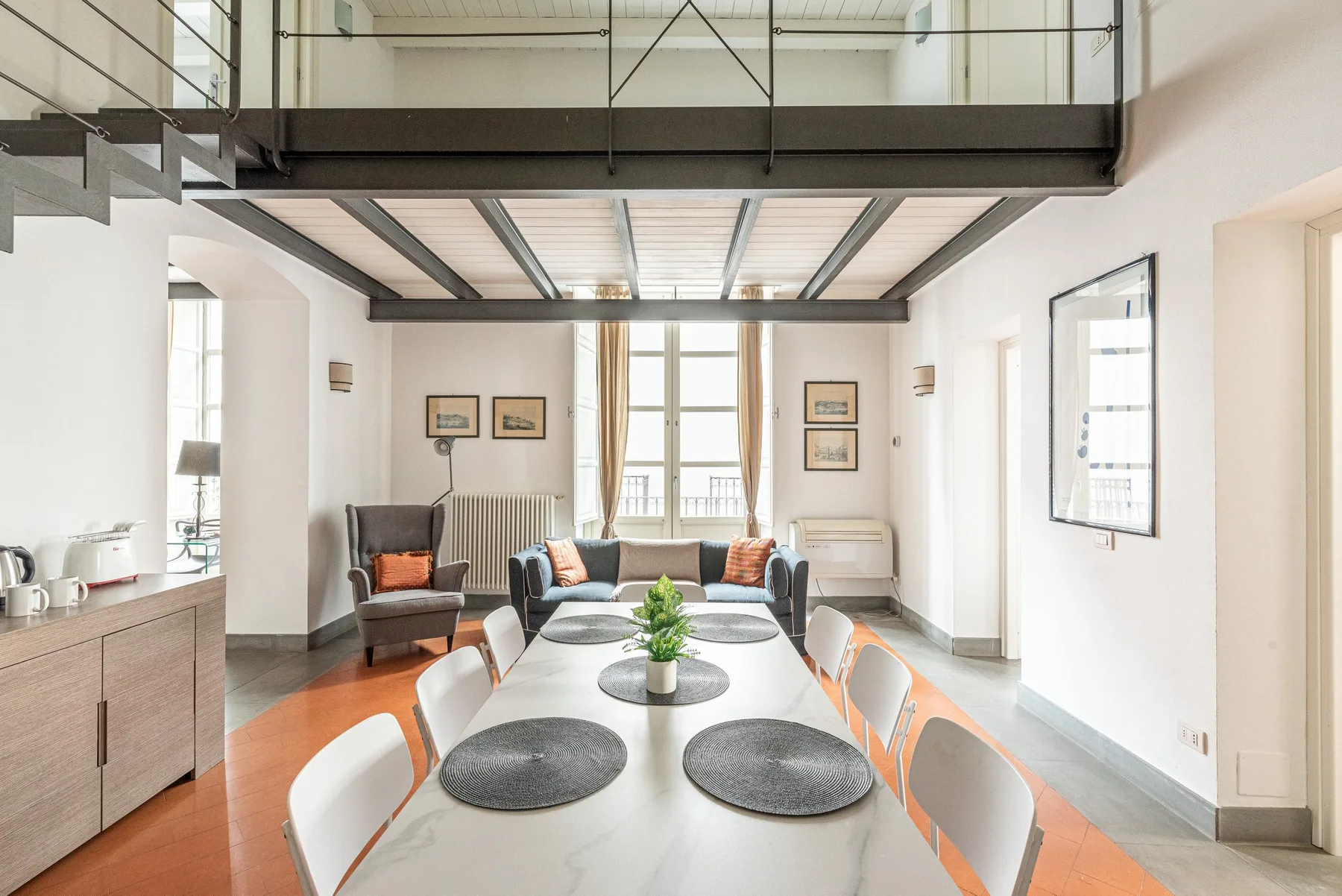 Un comedor luminoso con una mesa larga bajo un altillo.