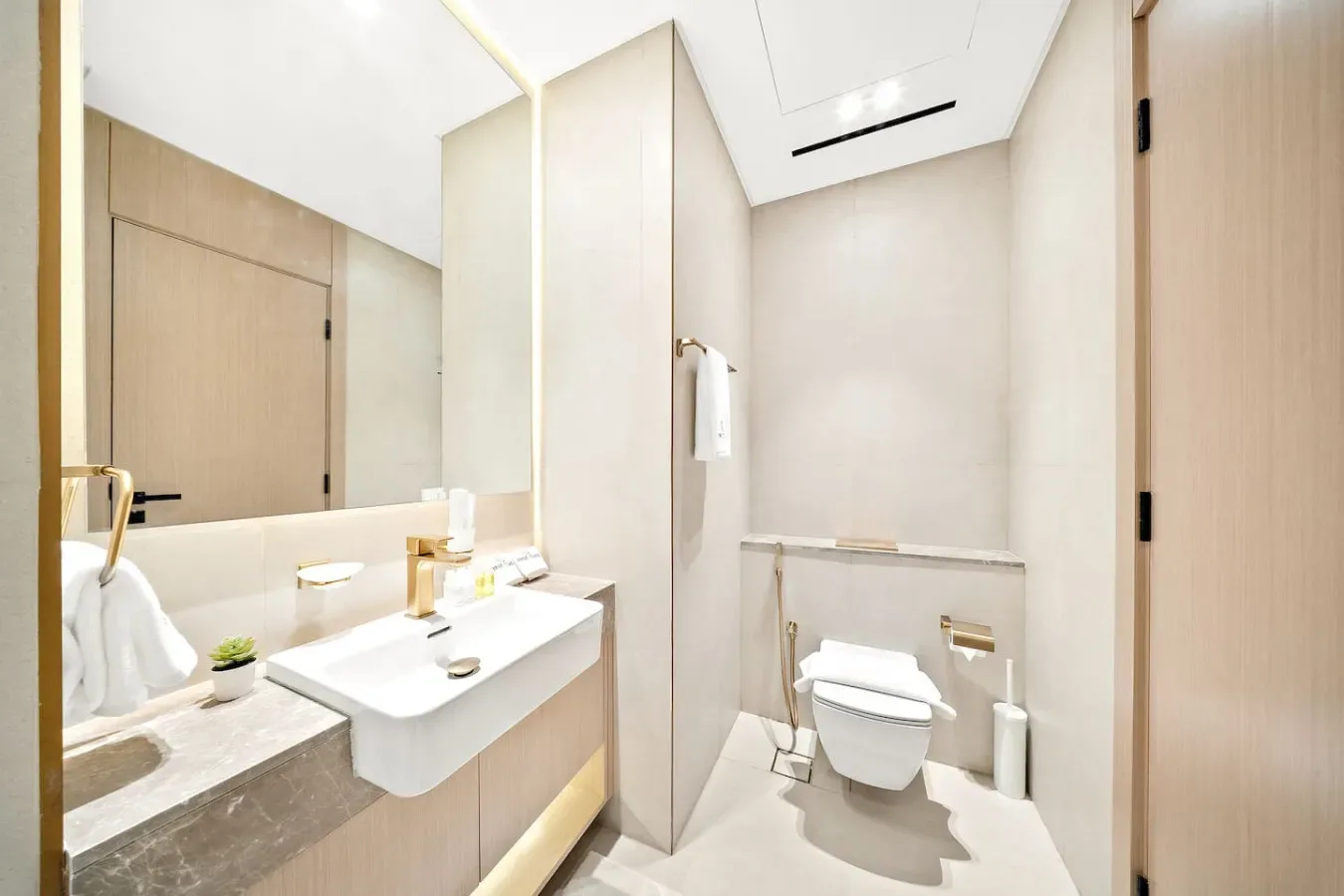 Un baño luminoso con lavabo, espejo e inodoro.