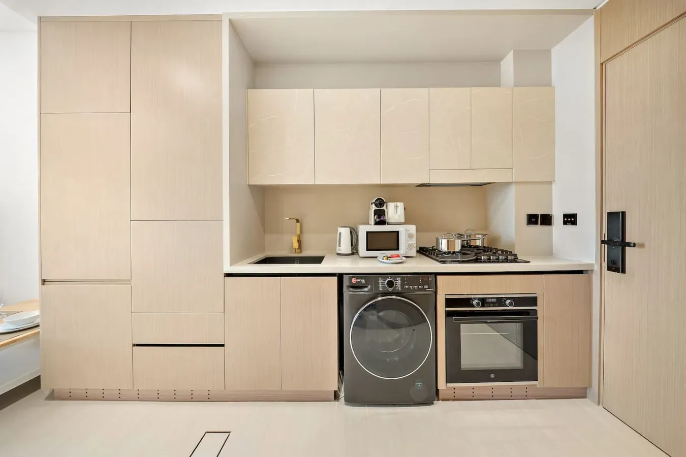 Una cocina compacta con gabinetes claros, encimera y electrodomésticos integrados.