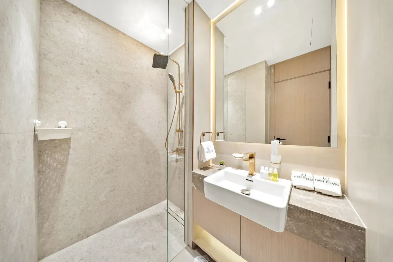 Un baño luminoso con una ducha de cristal y un lavabo bajo un espejo grande.
