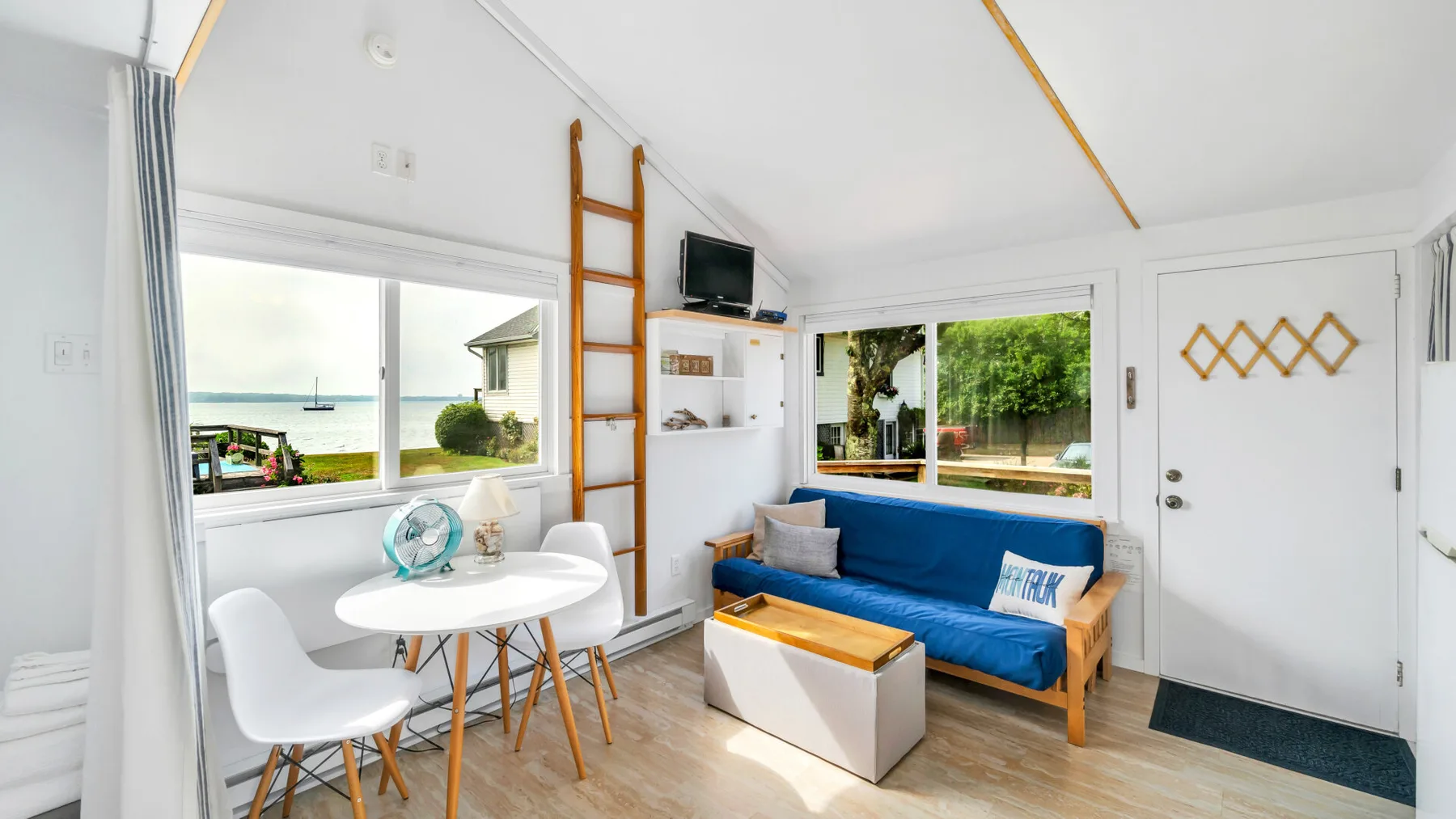 Una sala luminosa con asientos azules, una mesa de centro y ventanas amplias.
