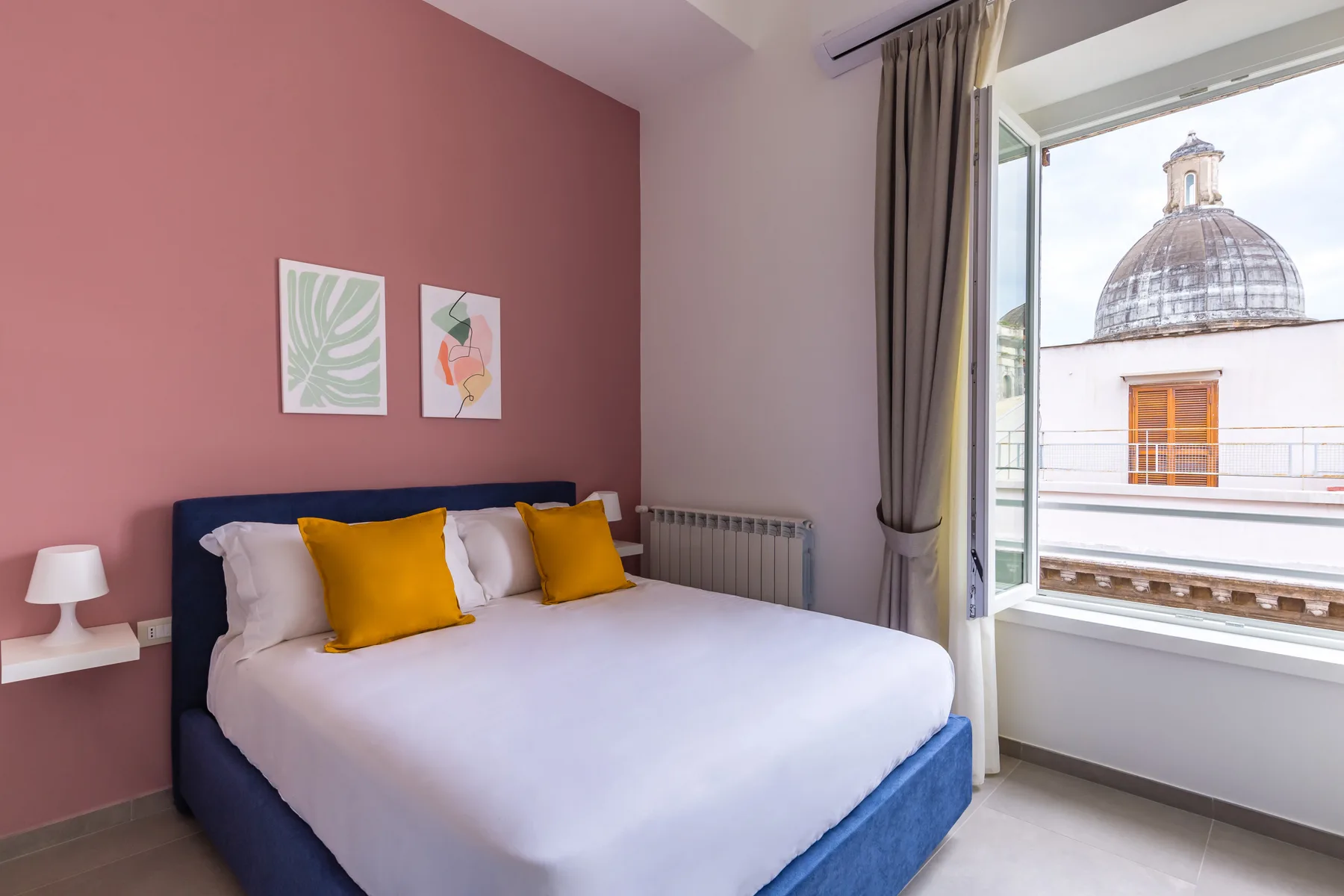 Un dormitorio con una cama bien hecha y una ventana abierta con vistas a una cúpula.