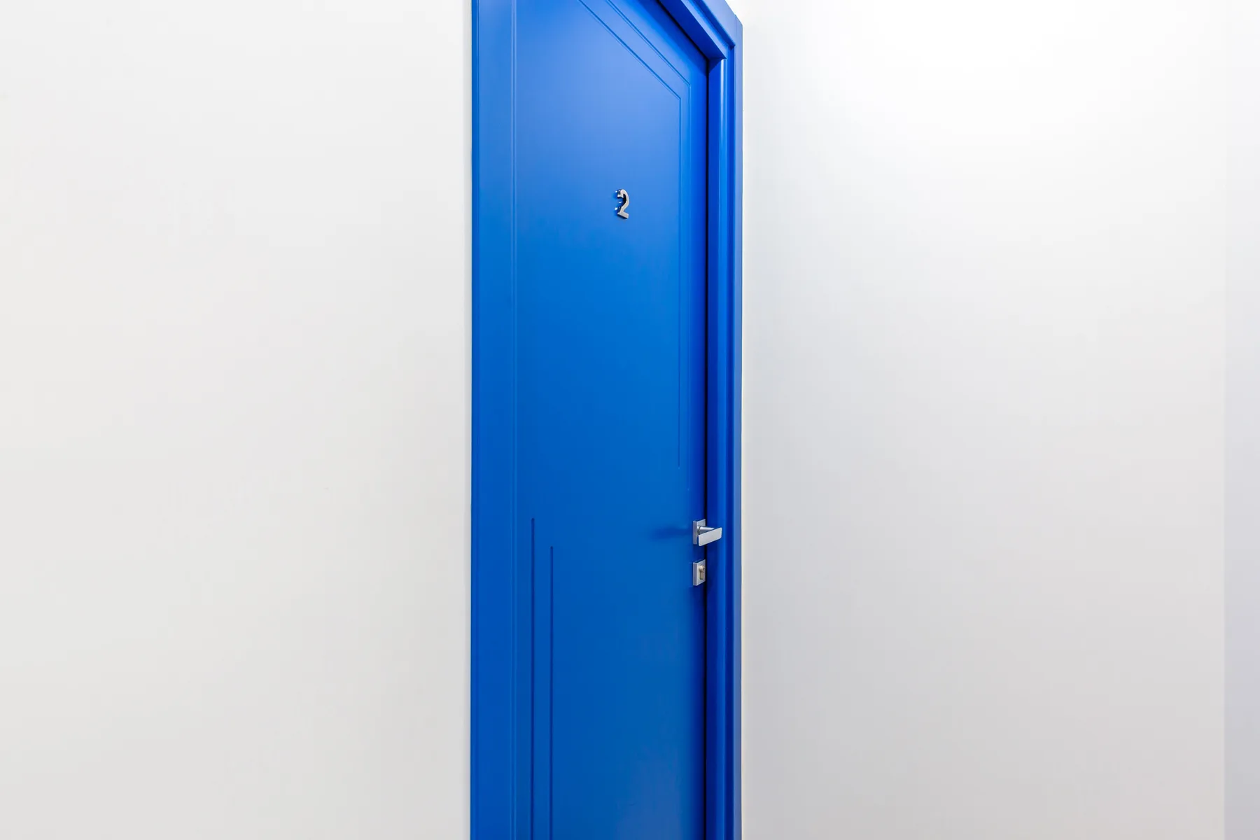 Una puerta azul se encuentra junto a una pared blanca lisa.