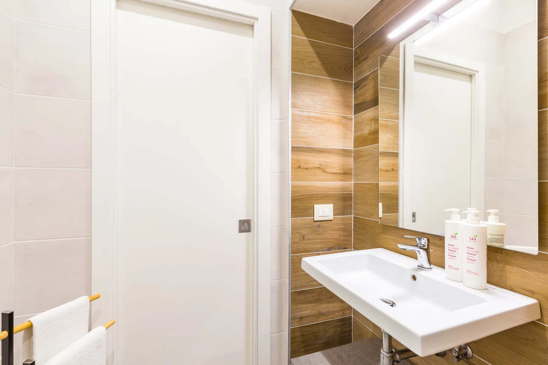 Un lavabo de baño está junto a una puerta blanca y un espejo.