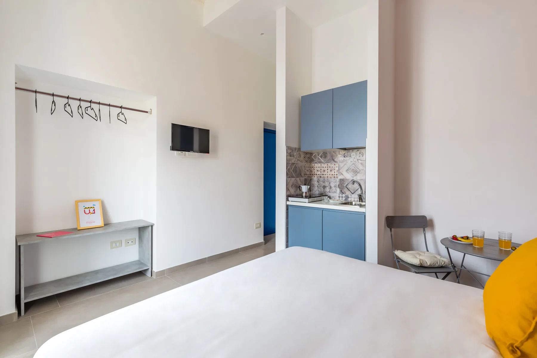 Una habitación luminosa con una cama y una pequeña zona de cocina.