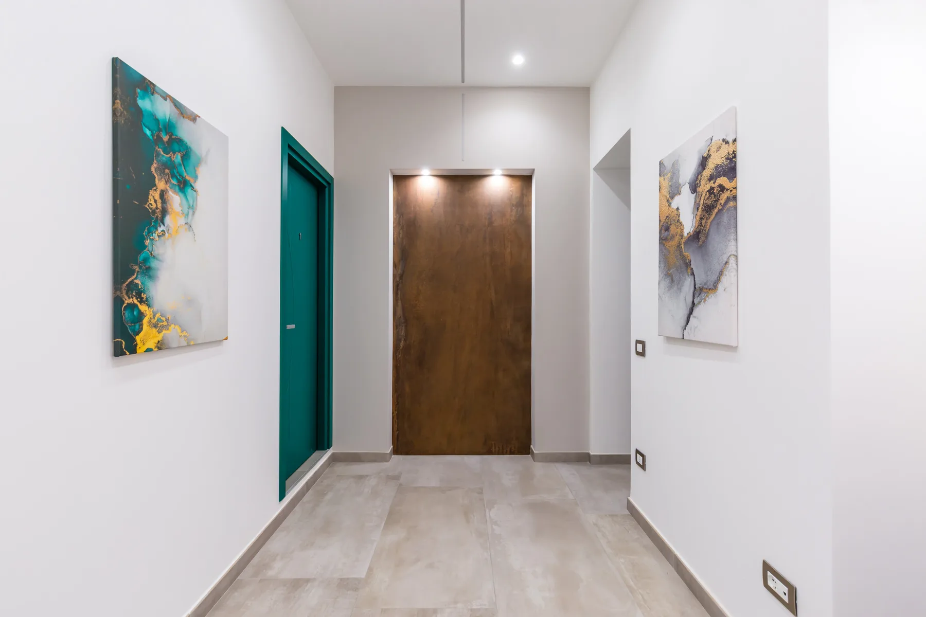 Un pasillo luminoso con una puerta de madera y arte abstracto en las paredes.