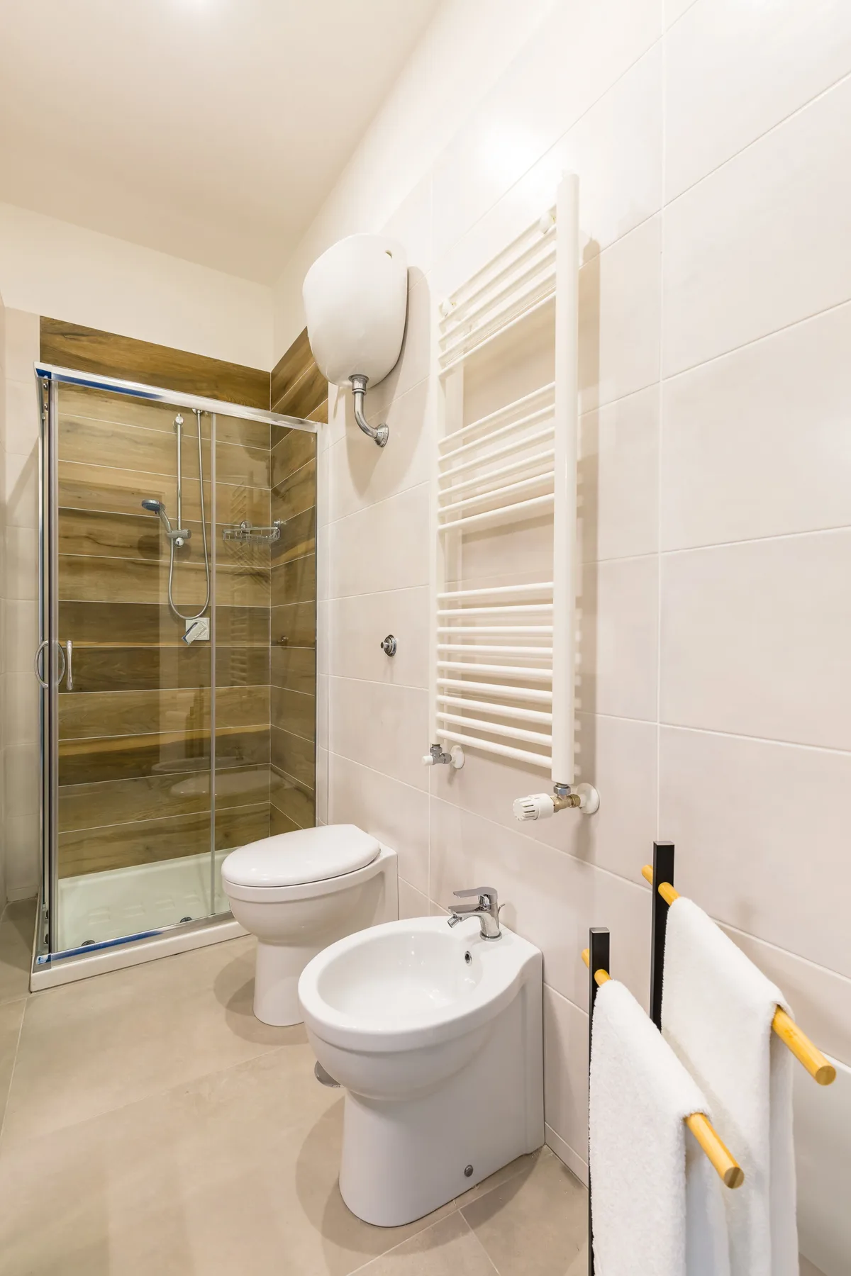 Un baño alicatado con ducha de vidrio, inodoro y bidé.