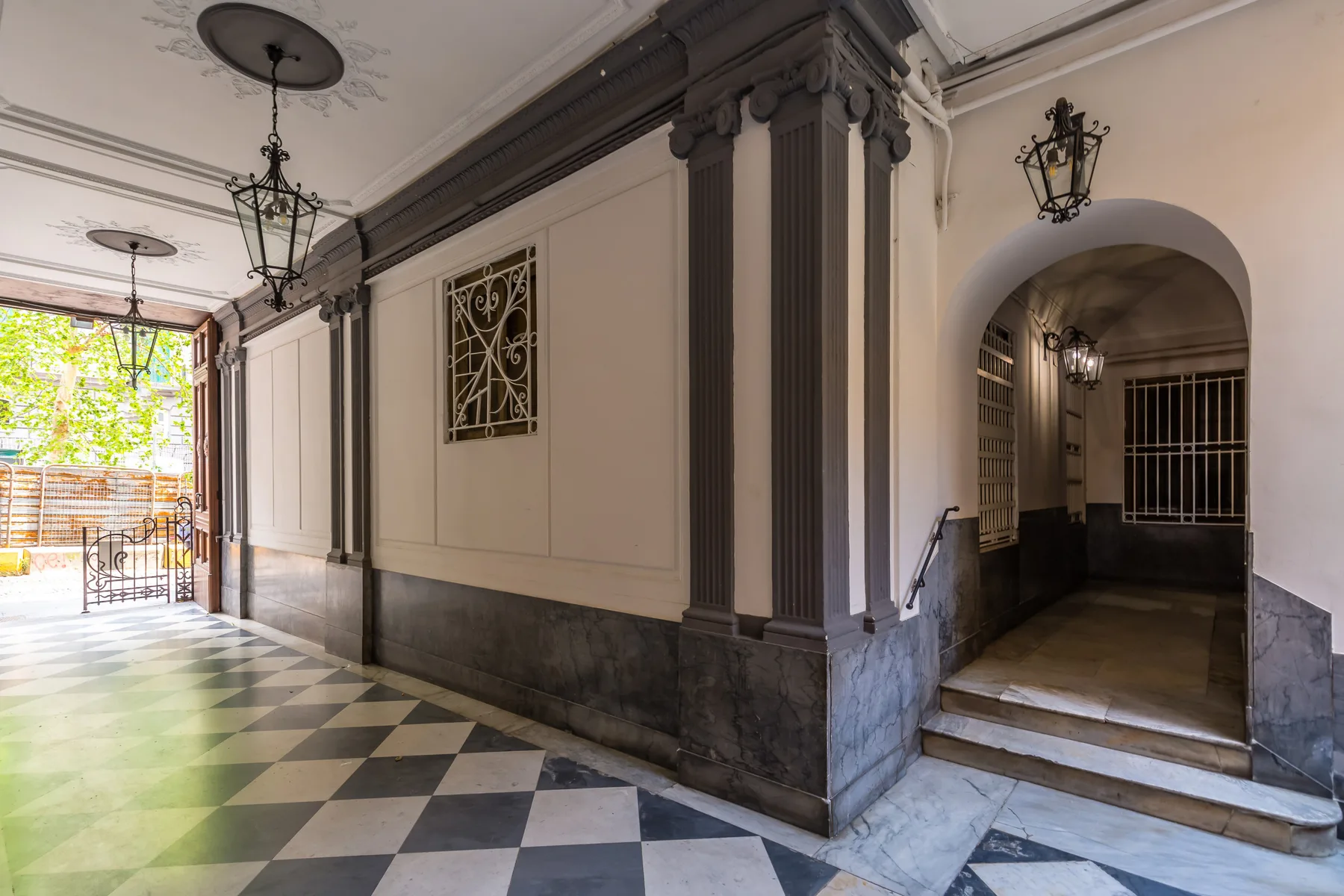 Un pasillo interior decorado tiene un suelo de cuadros y un paso arqueado.