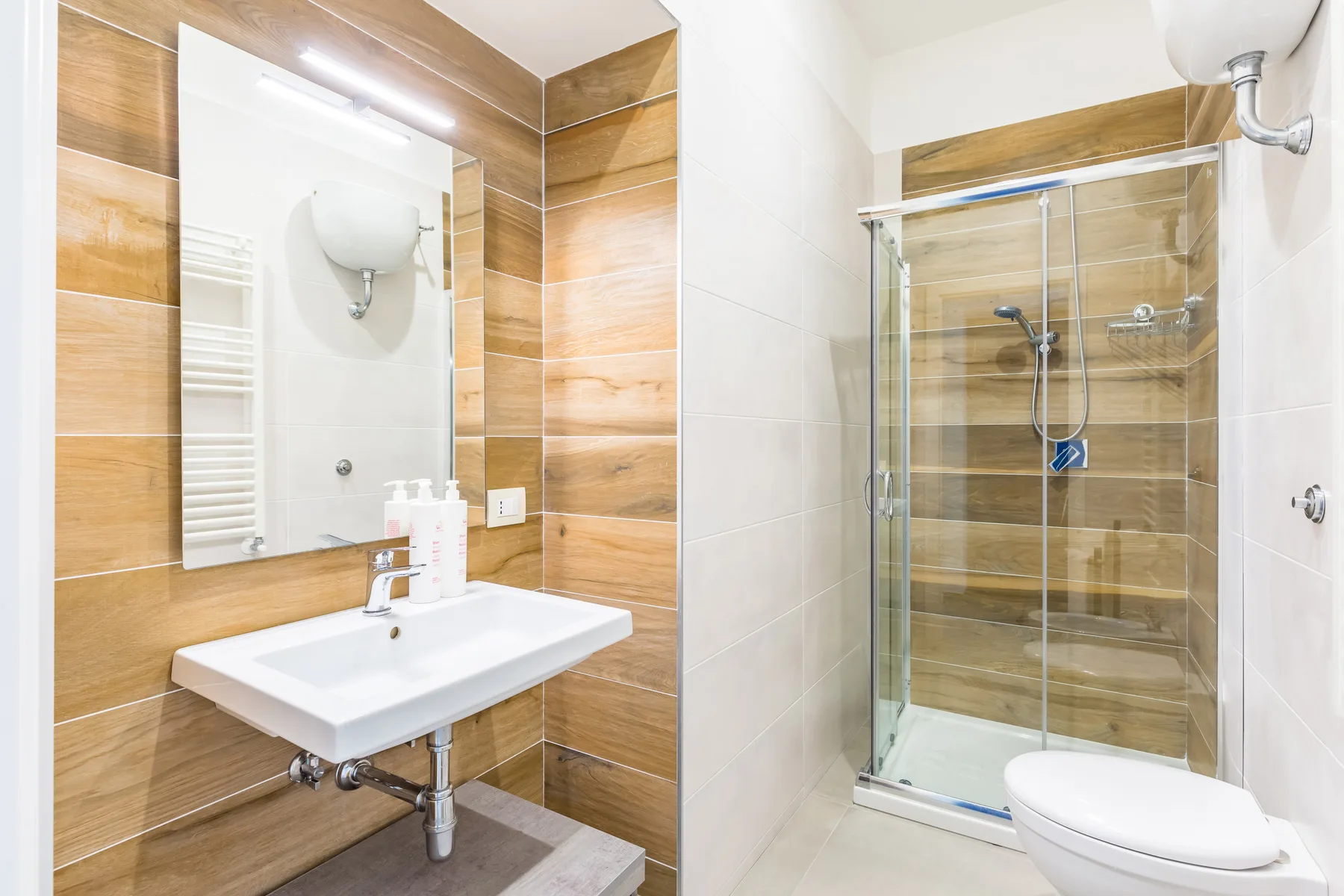 Un baño con lavabo, espejo, ducha e inodoro.