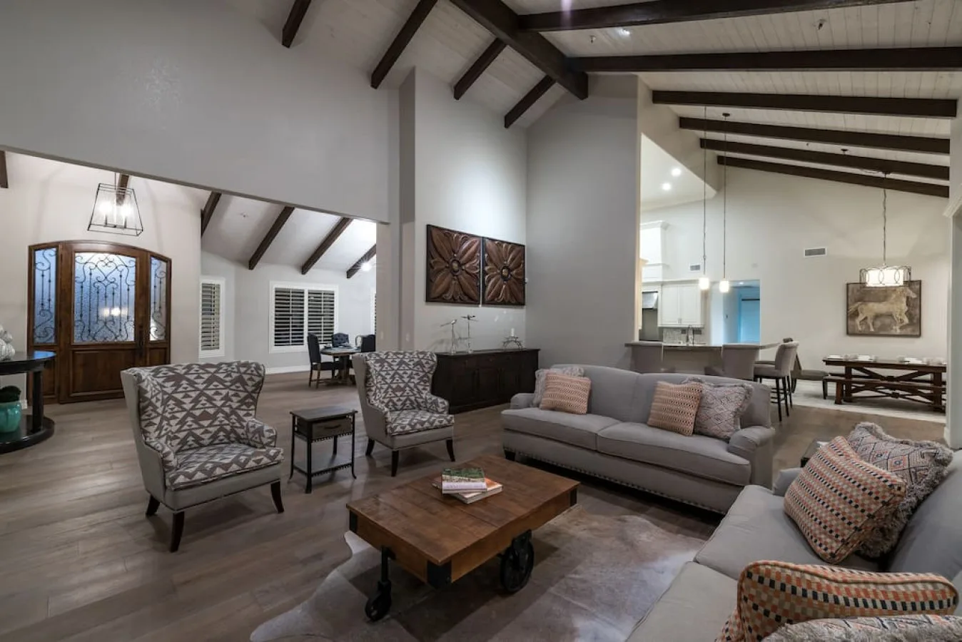 A living room with seating arranged around a wooden coffee table beneath exposed ceiling beams.