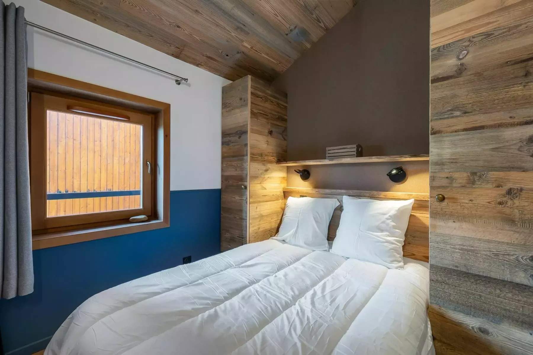 A bedroom with two beds beneath a wooden ceiling.