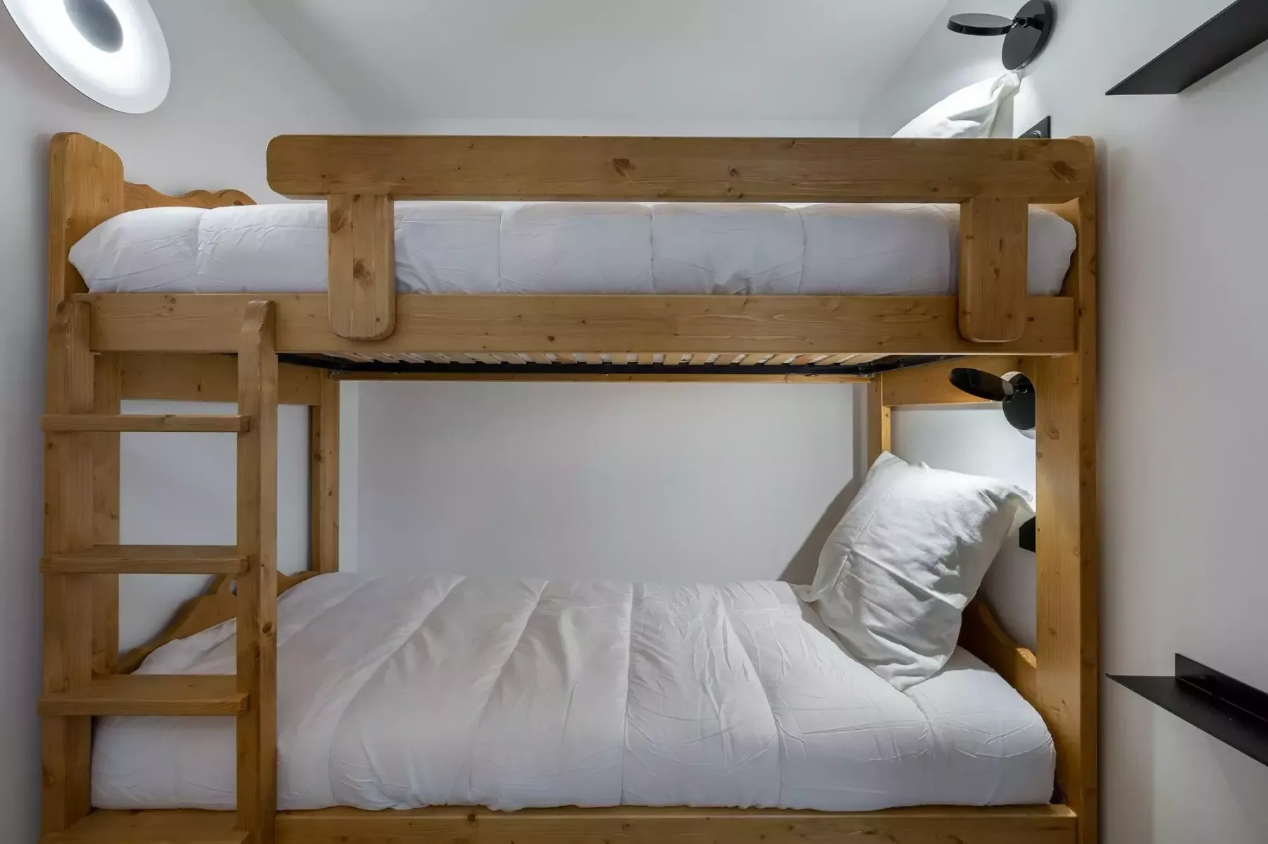 Un dormitorio compacto con una litera de madera y ropa de cama blanca.