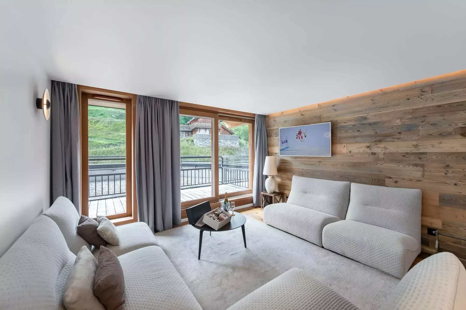 Sala de estar con asientos alrededor de una mesa de centro junto a grandes ventanas.