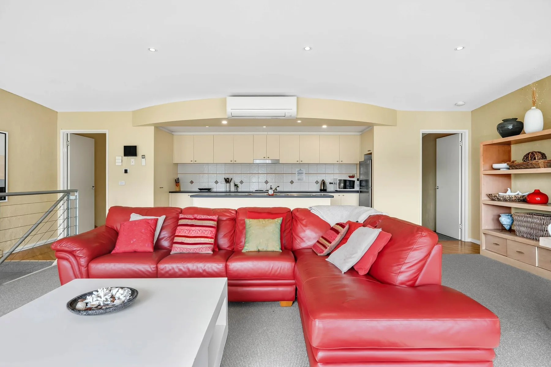 A bright living room with red seating and an open kitchen behind it.