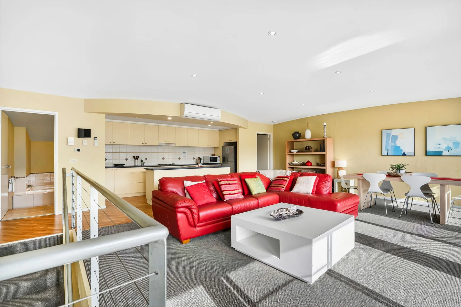 Living room with red seating, a coffee table, and an open kitchen.