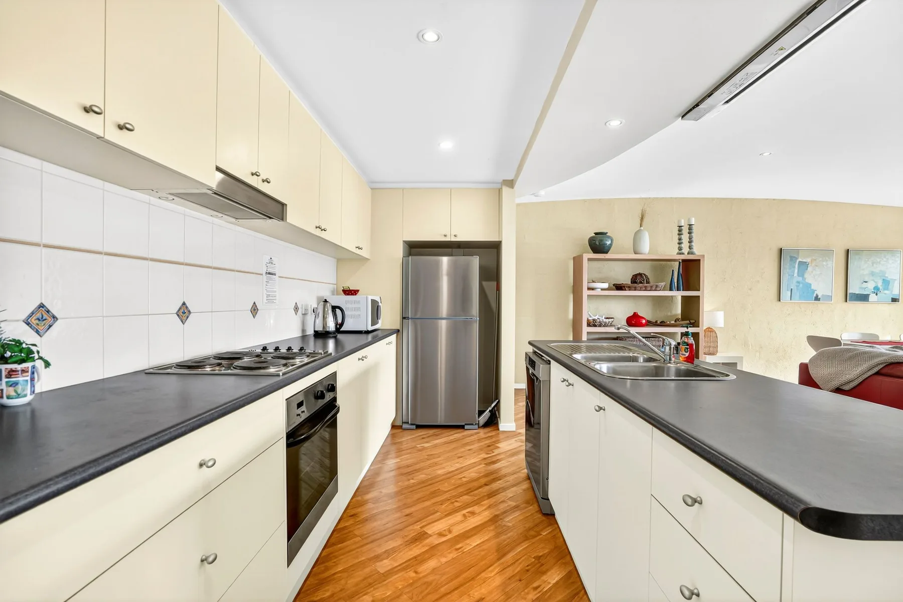 A bright kitchen with counters, cabinets, and a stainless steel refrigerator.