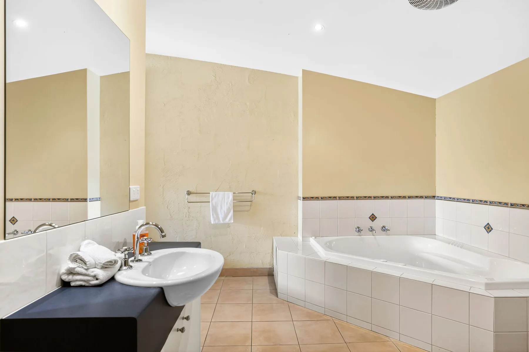 A bathroom with a large bathtub and a sink beside the mirror.