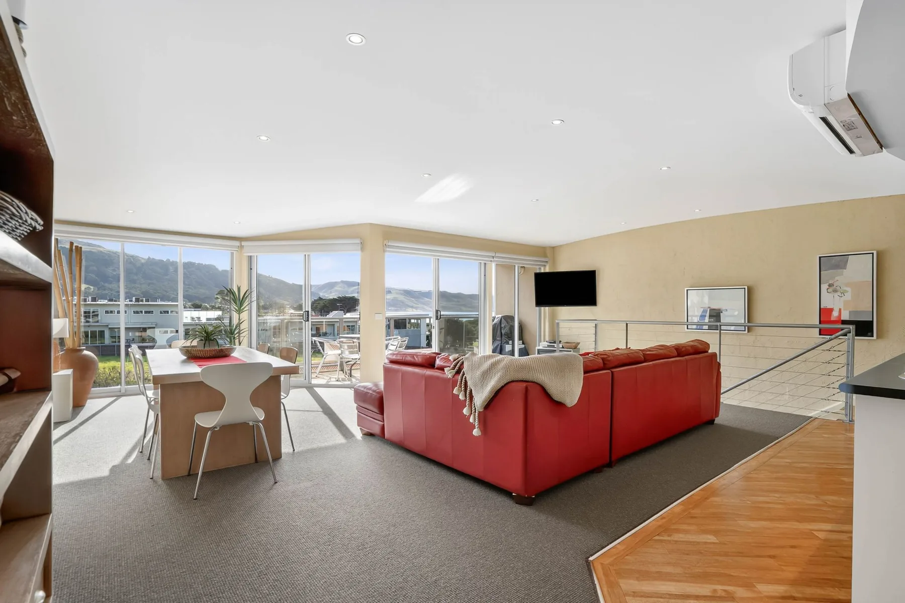 A bright living room with red seating and large windows overlooking the outdoors.