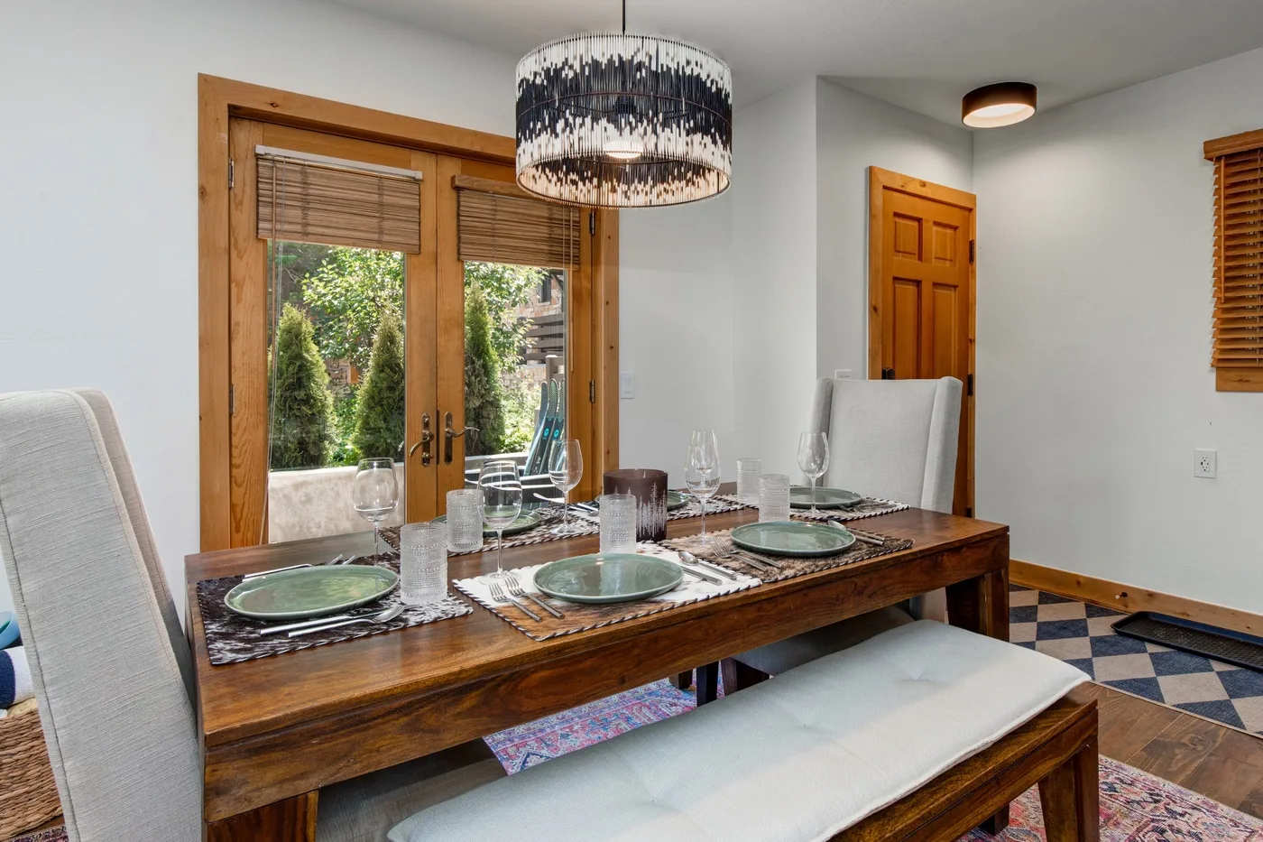 Un comedor con una mesa de madera preparada para comer junto a puertas de vidrio.