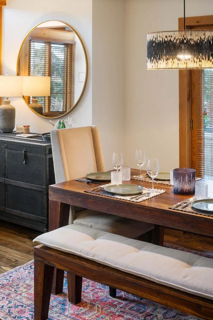 Un comedor con una mesa de madera, un banco y vajilla puesta.