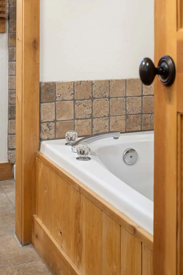 Un baño con una bañera empotrada, azulejos en la pared y paneles de madera.