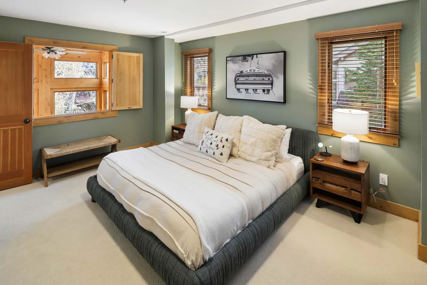 Un dormitorio con una cama tendida y ventanas con persianas de madera.