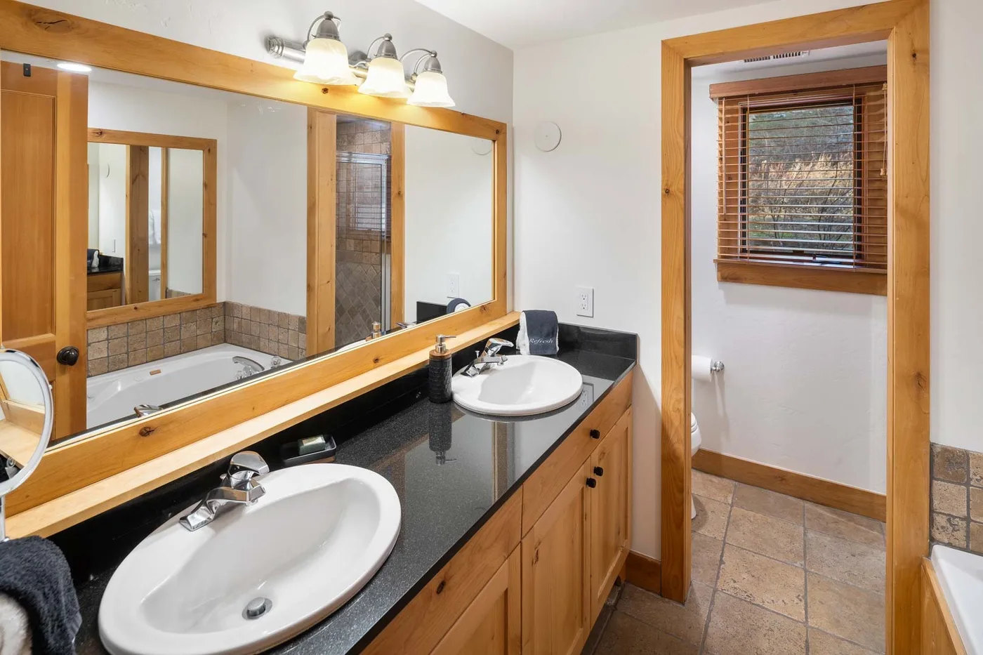 Un tocador de baño con lavabos y un espejo grande junto a una ventana.