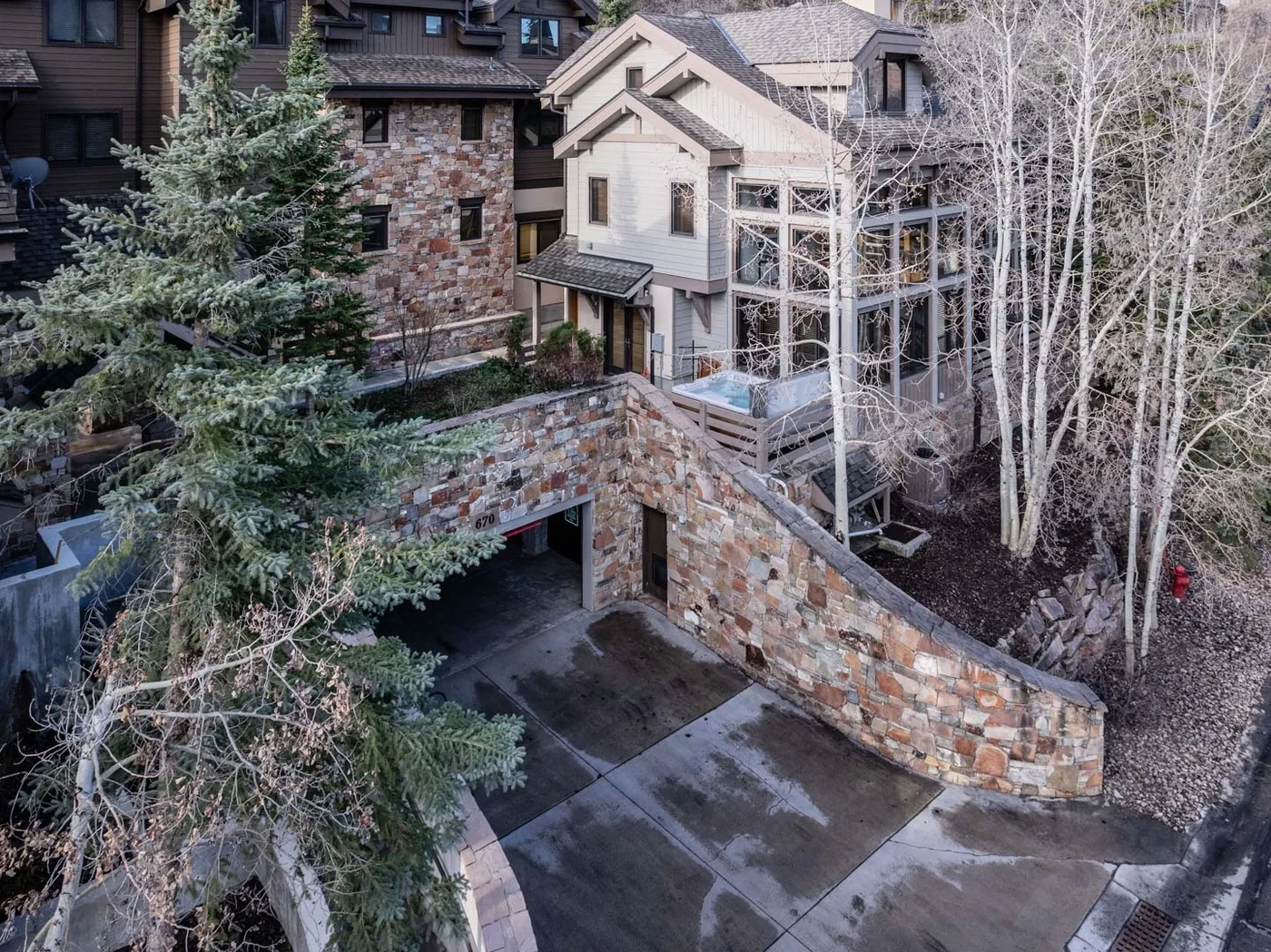 Un edificio revestido de piedra con un muro curvo y una entrada pavimentada.