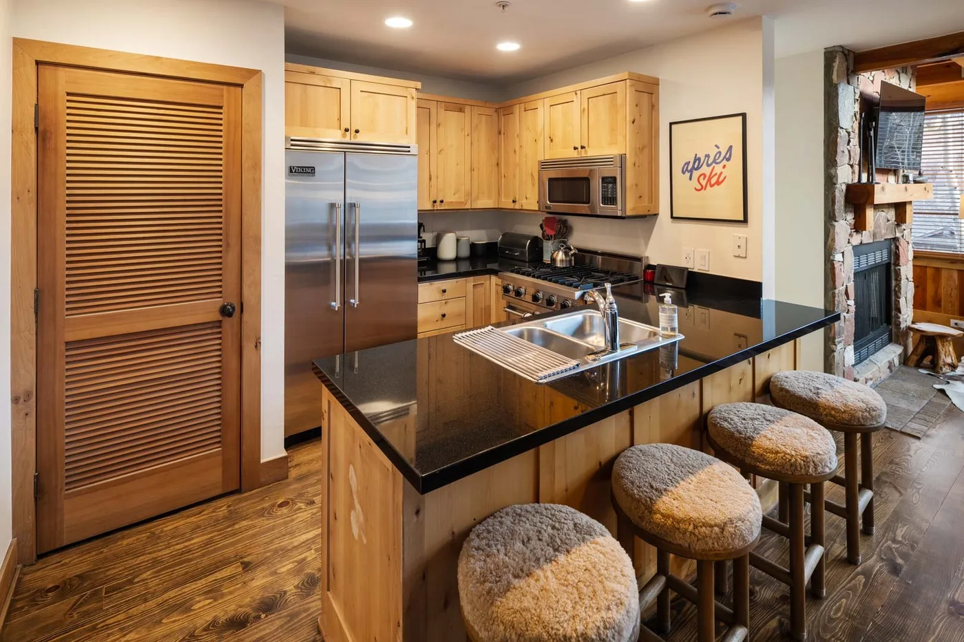 Una cocina con gabinetes de madera, electrodomésticos de acero inoxidable y una barra con asientos.
