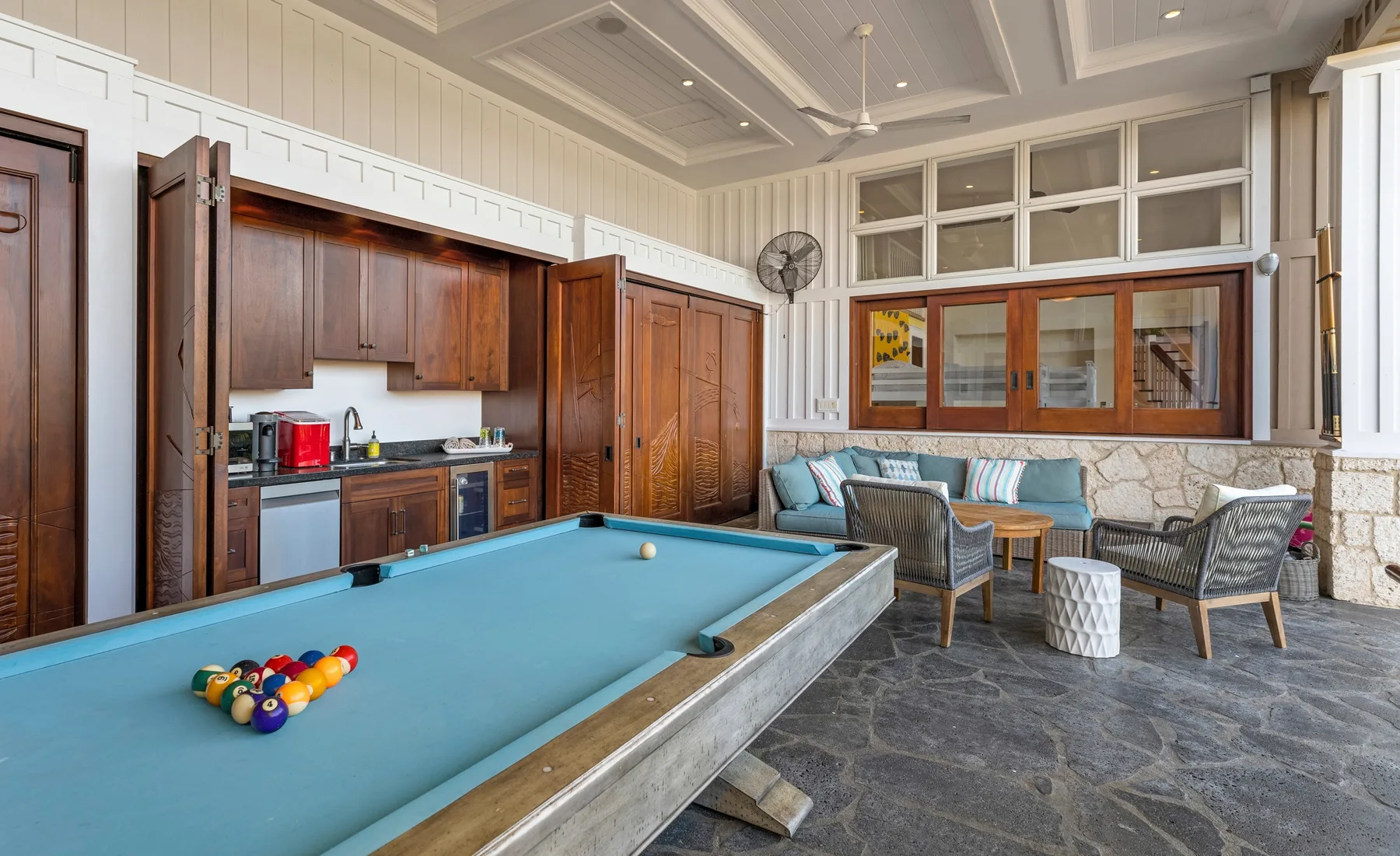 Una sala de juegos con mesa de billar, asientos y una pequeña cocina.
