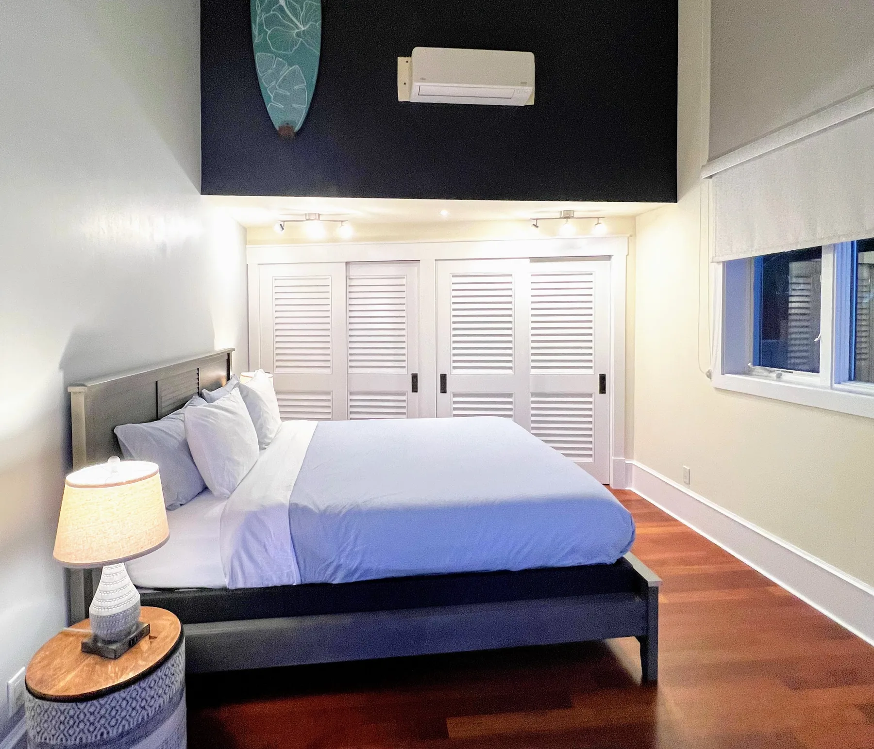Un dormitorio con una cama, puertas con persianas y una ventana.