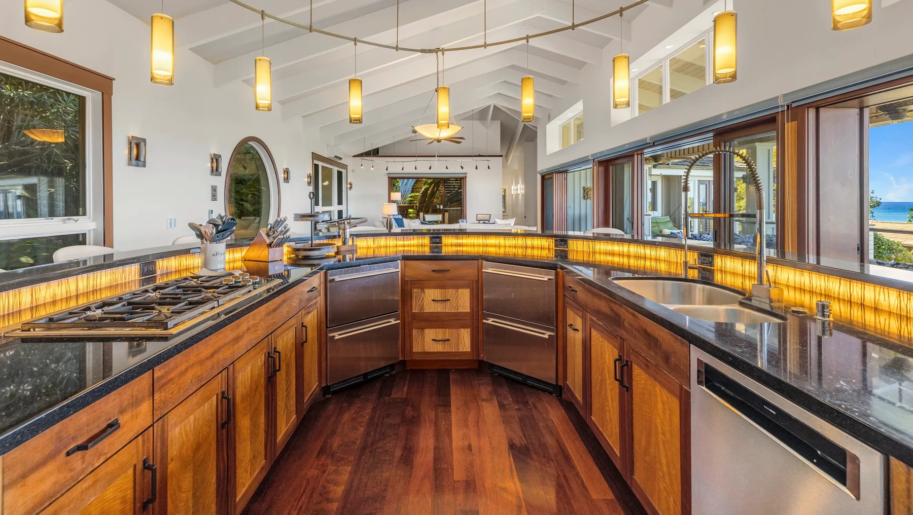 Una cocina amplia con gabinetes de madera, encimeras oscuras y luces colgantes.