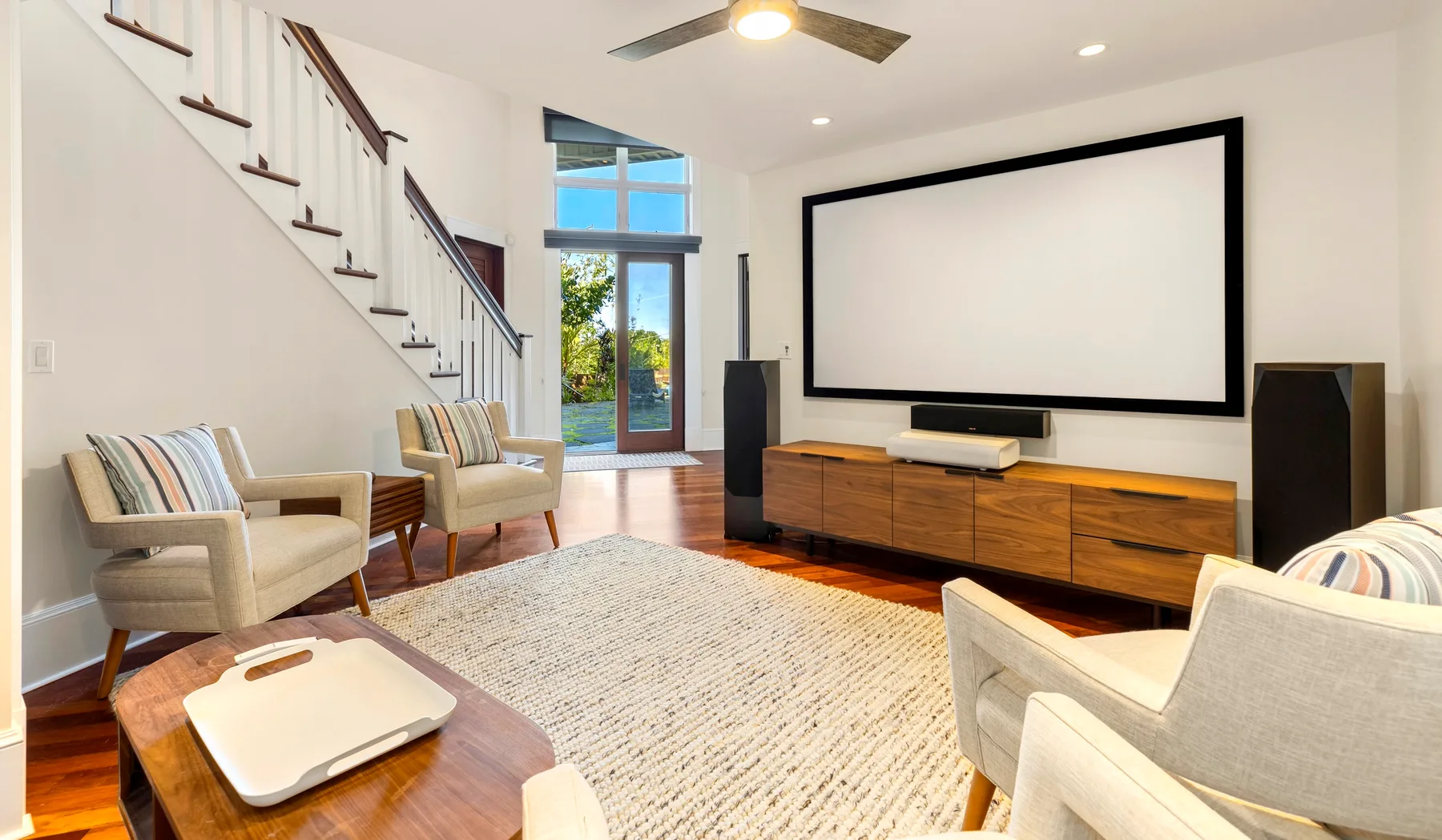 Una sala de estar luminosa con una pantalla grande sobre un mueble de madera.