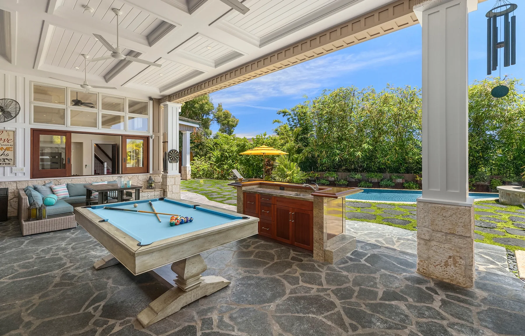 Una zona de juegos exterior cubierta con una mesa de billar y una piscina al fondo.
