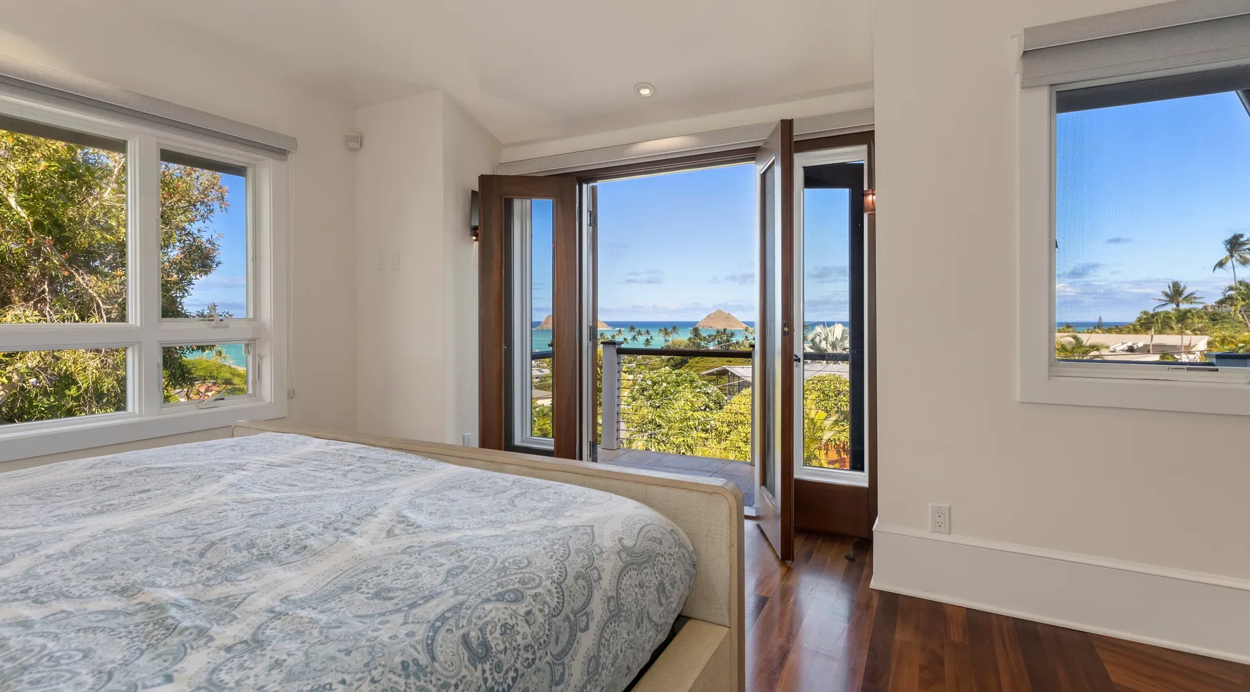 Un dormitorio con una cama junto a puertas abiertas con vistas al mar.