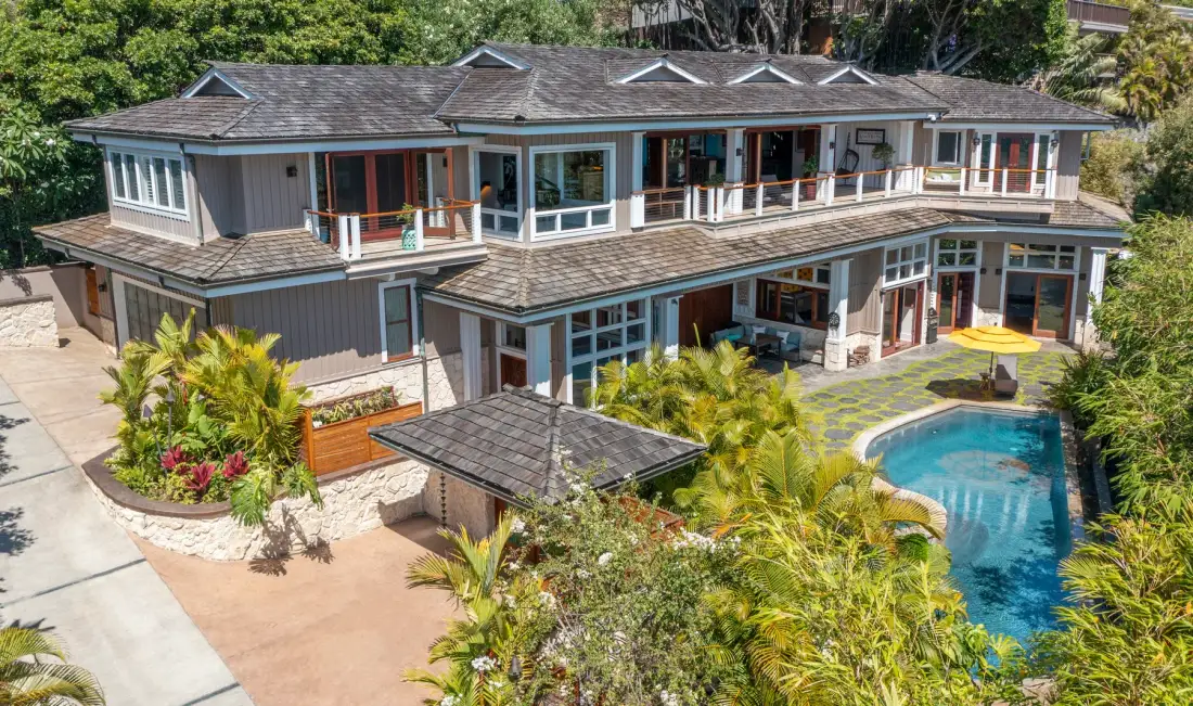 Una casa grande con balcones y una piscina rodeada de vegetación.
