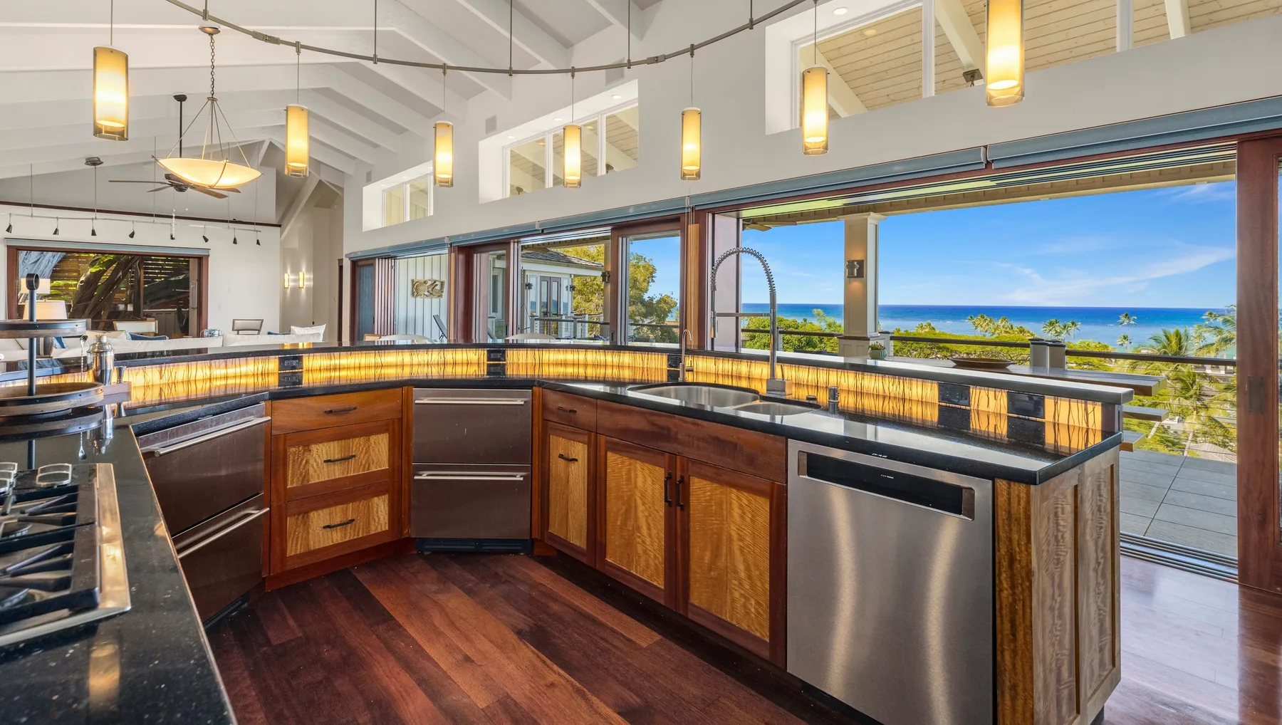 Una cocina amplia con una isla central, gabinetes de madera y vistas al océano.
